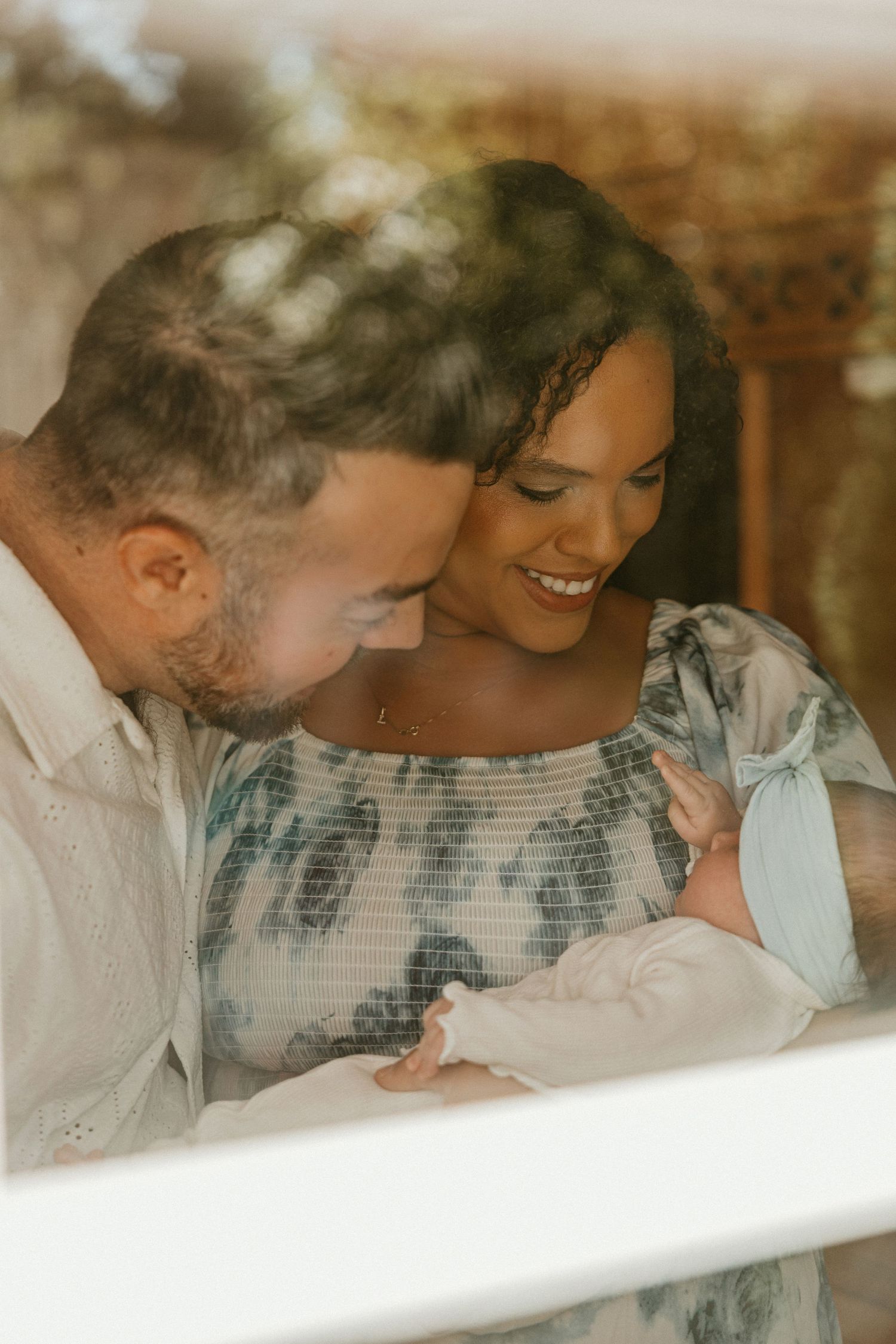 Intimate family moment captured through window with soft lighting.