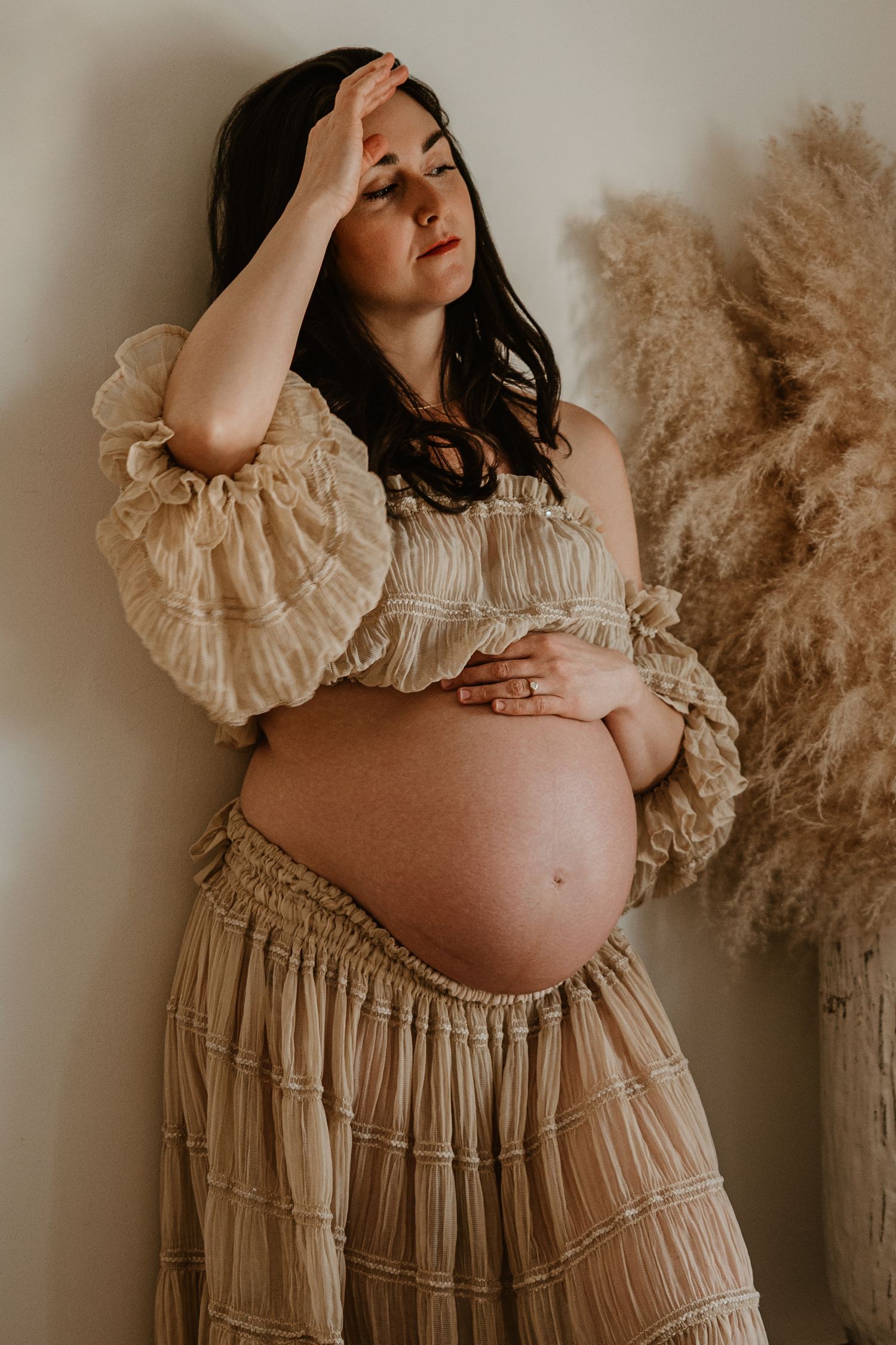 Dreamy maternity portrait in cream-colored dress with pampas grass decor.
