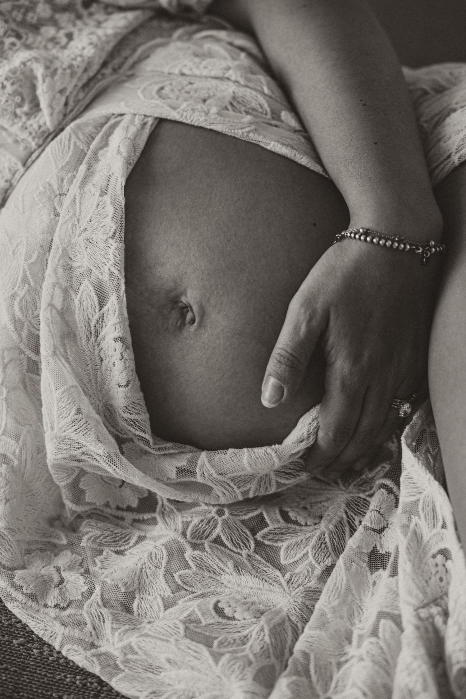 Artistic black and white maternity photo showcasing delicate lace fabric details.