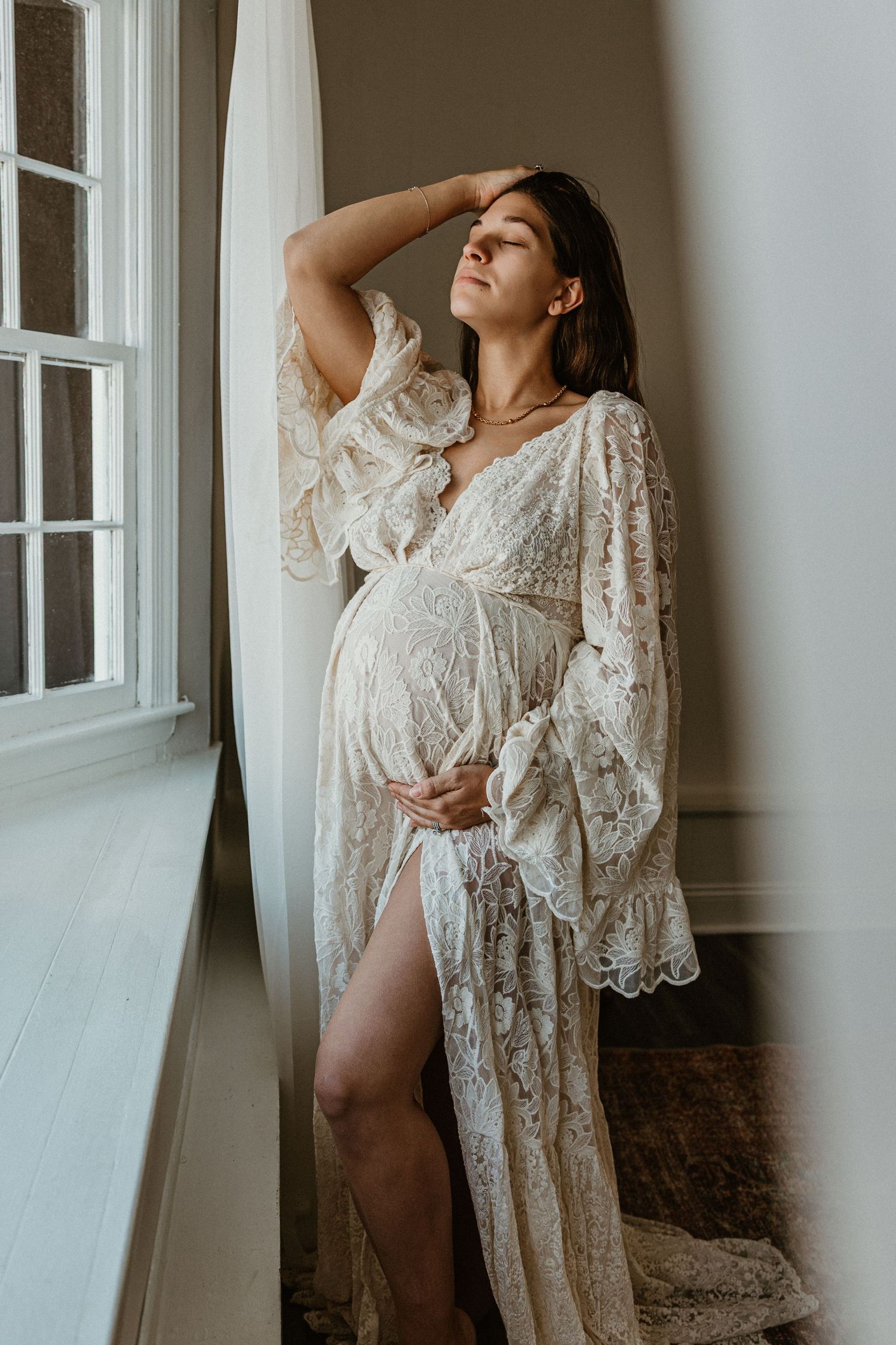 Elegant boudoir portrait session with white lace robe against minimalist white walls.