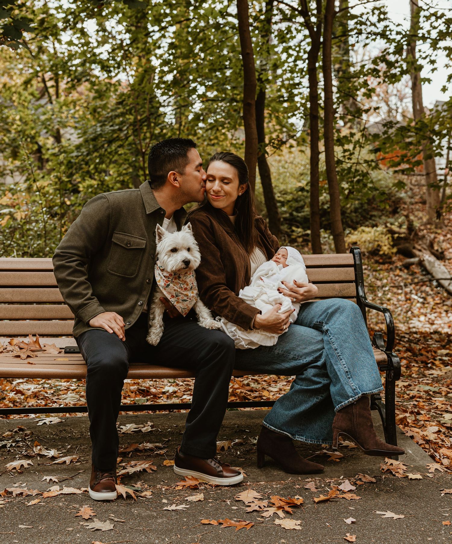 Family walking together on a park bench surrounded by autumn leaves.