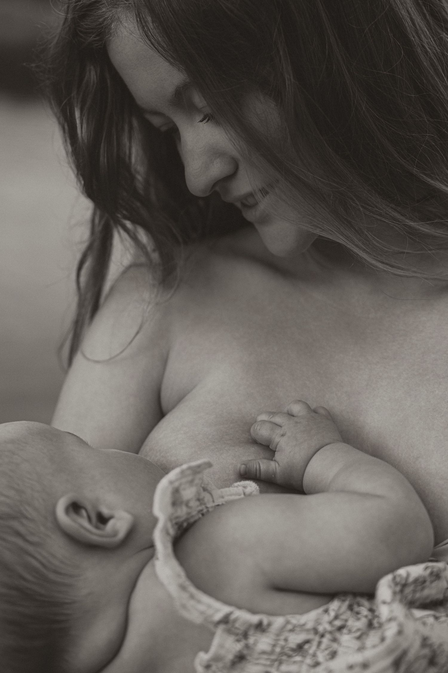 Black and white photo of a mother breastfeeding her newborn baby, a tender and intimate moment of bonding.
