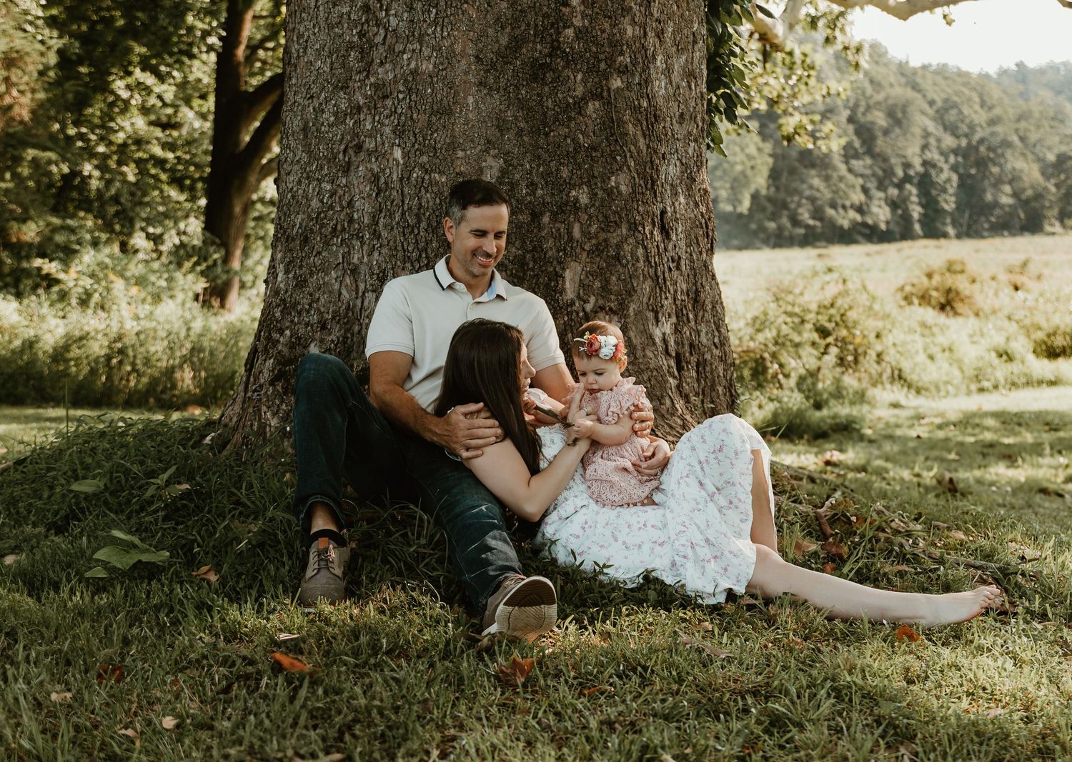 Family spending time together under shade tree in park.