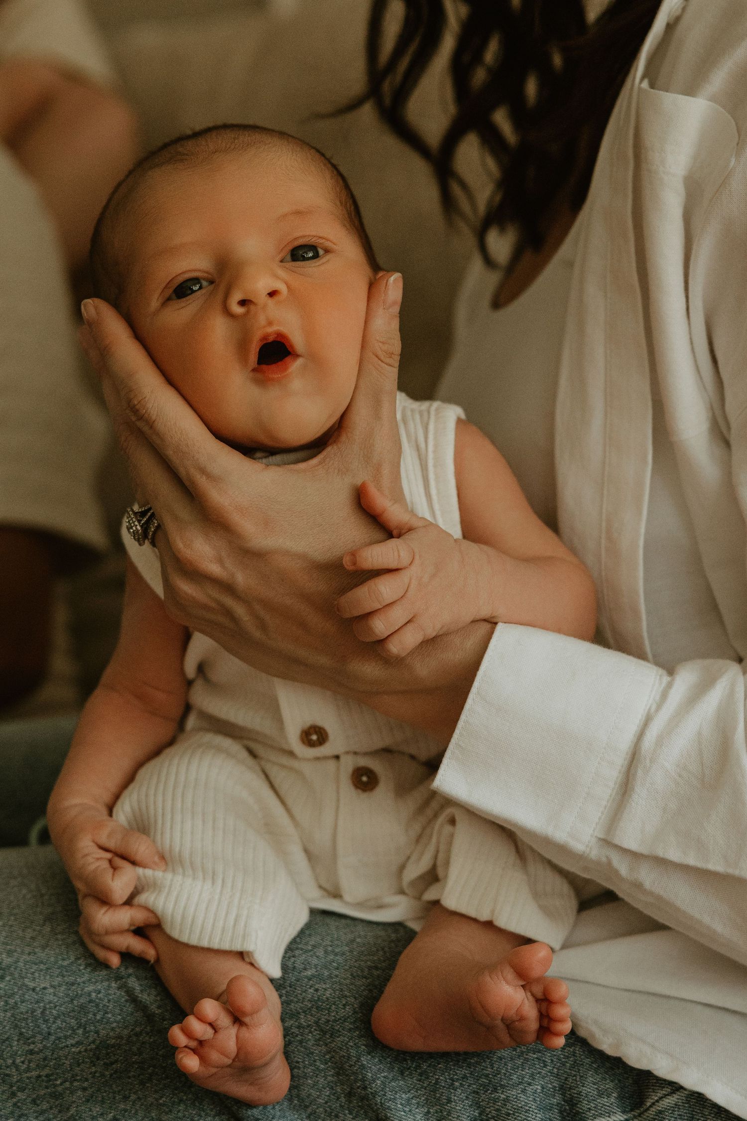 Close-up of an alert newborn baby being gently held by their mother's hands.
