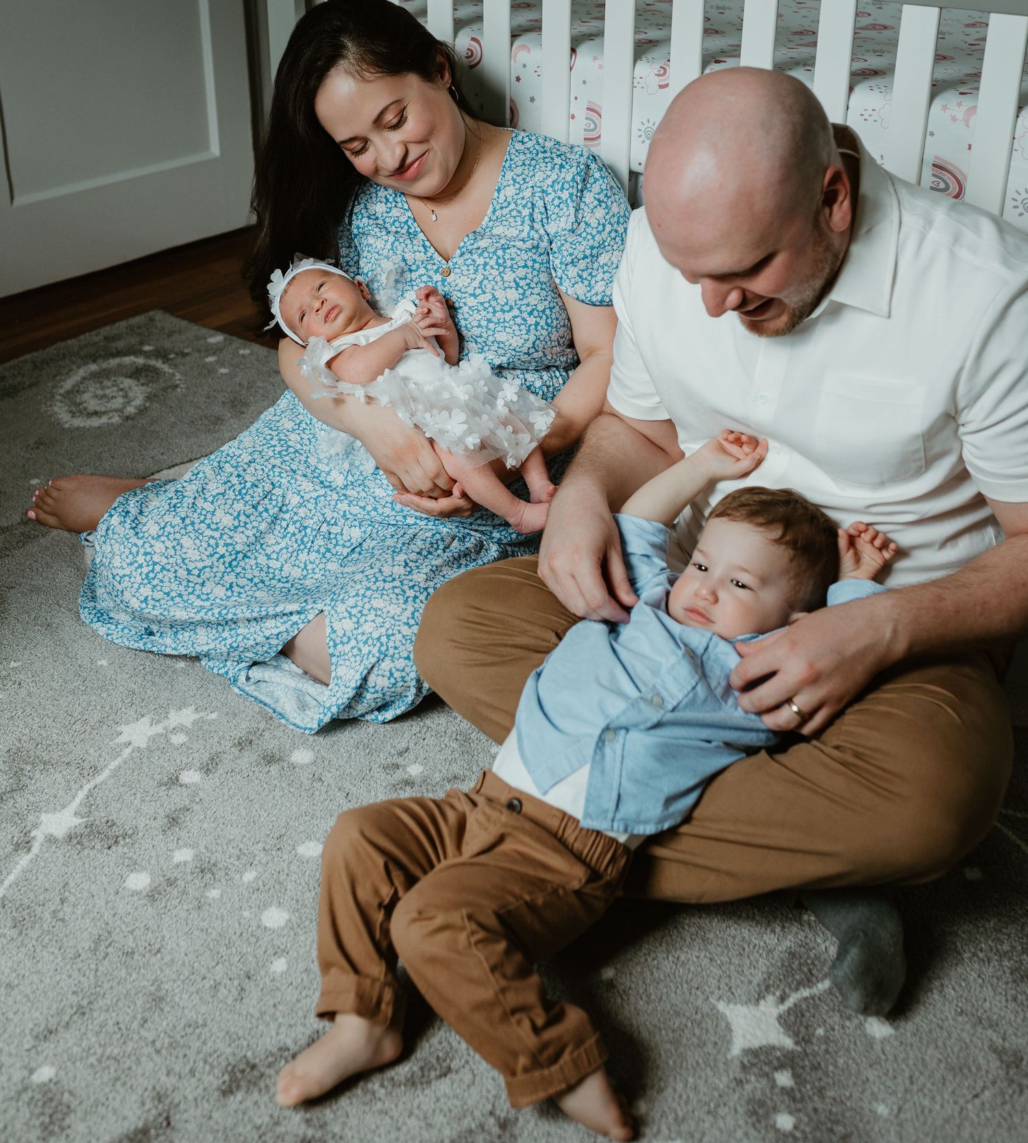 Intimate family moments captured on a soft gray carpet in natural light.