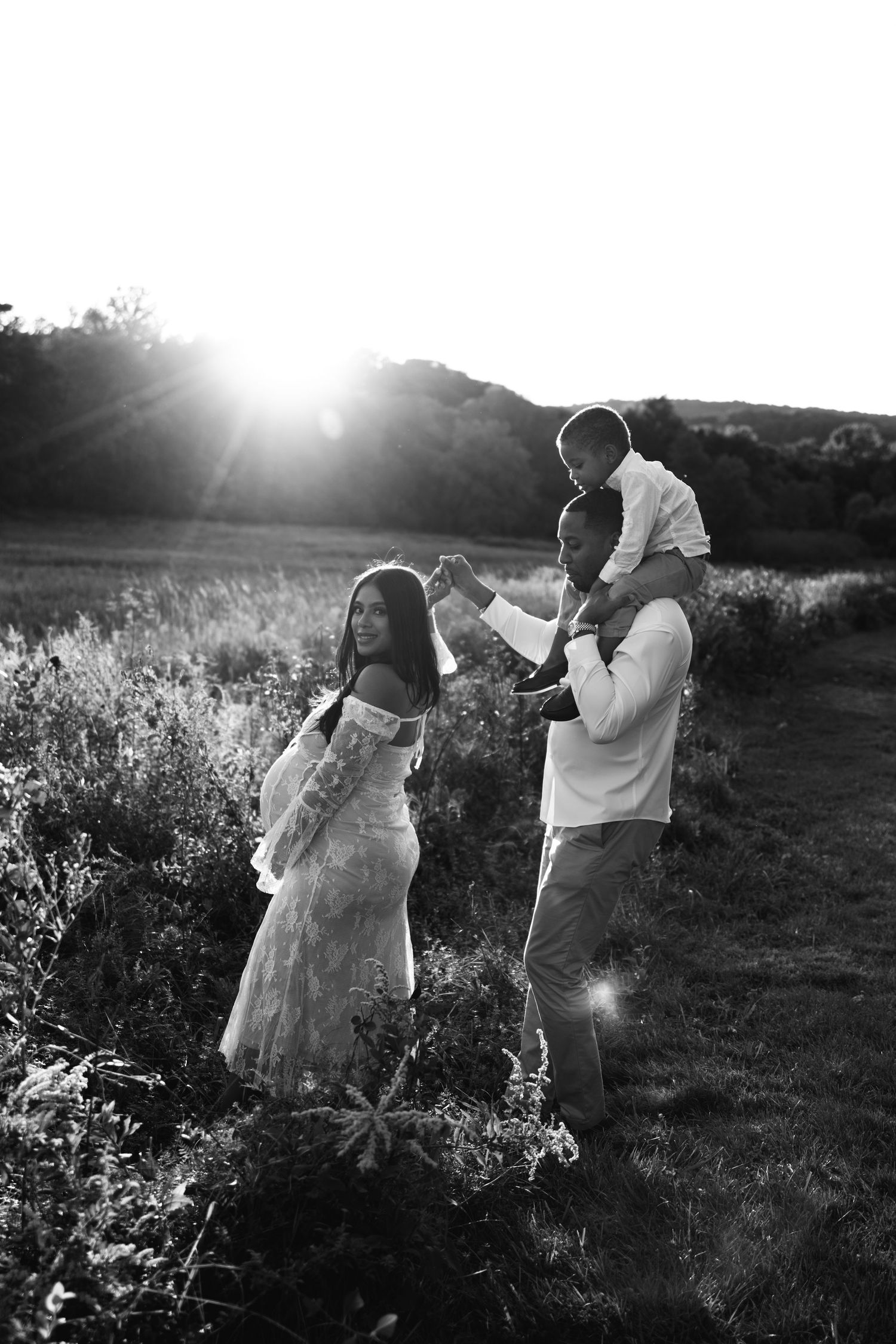 Silhouetted family dancing together in a field during sunset.