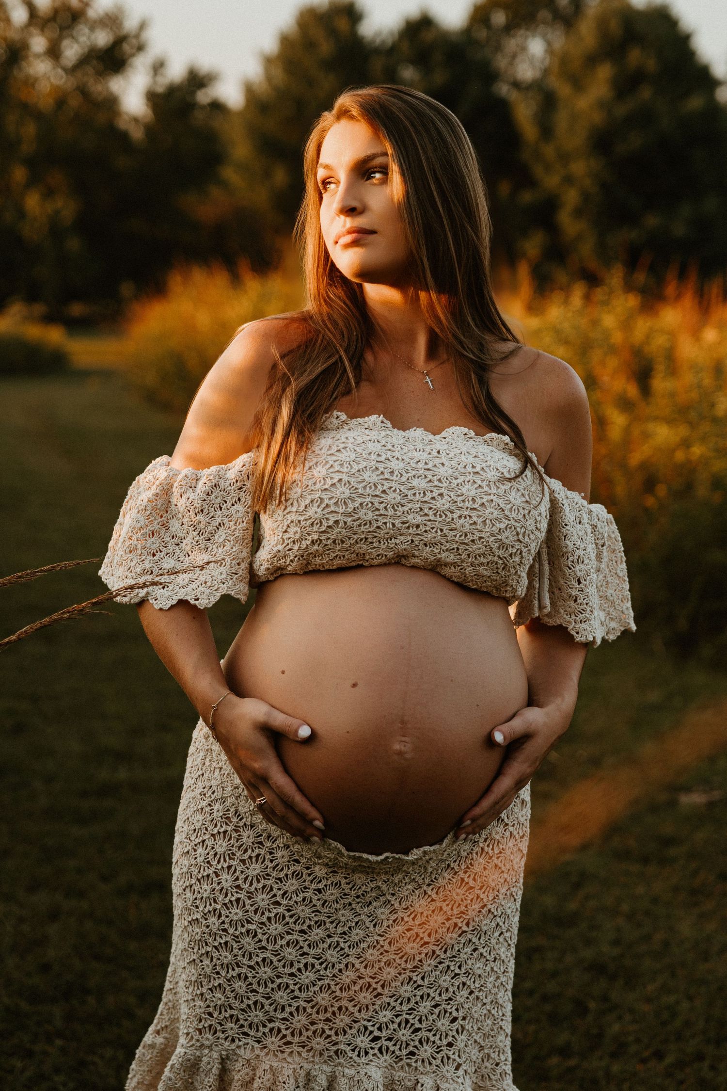 Dramatic maternity portrait in lace dress with autumn colors in background.