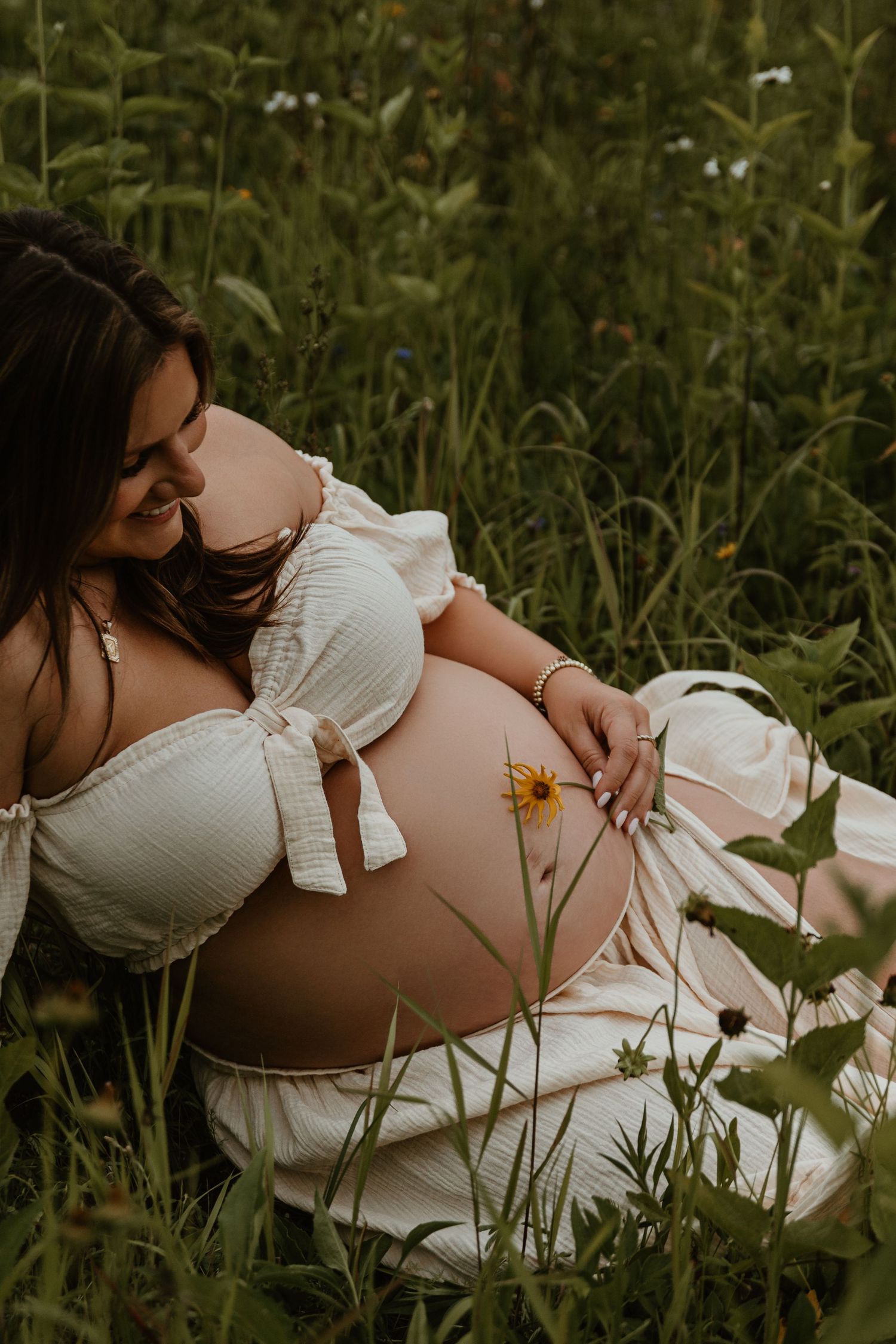 Artistic maternity photos taken in natural outdoor setting with tall grass.