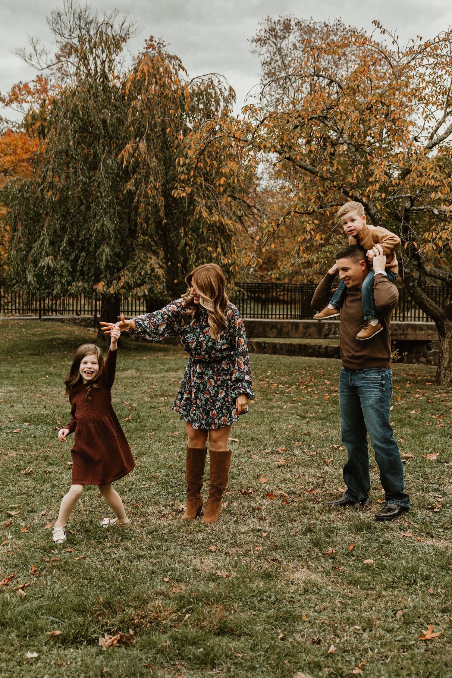 Family playing and dancing together on grass during fall photo session.
