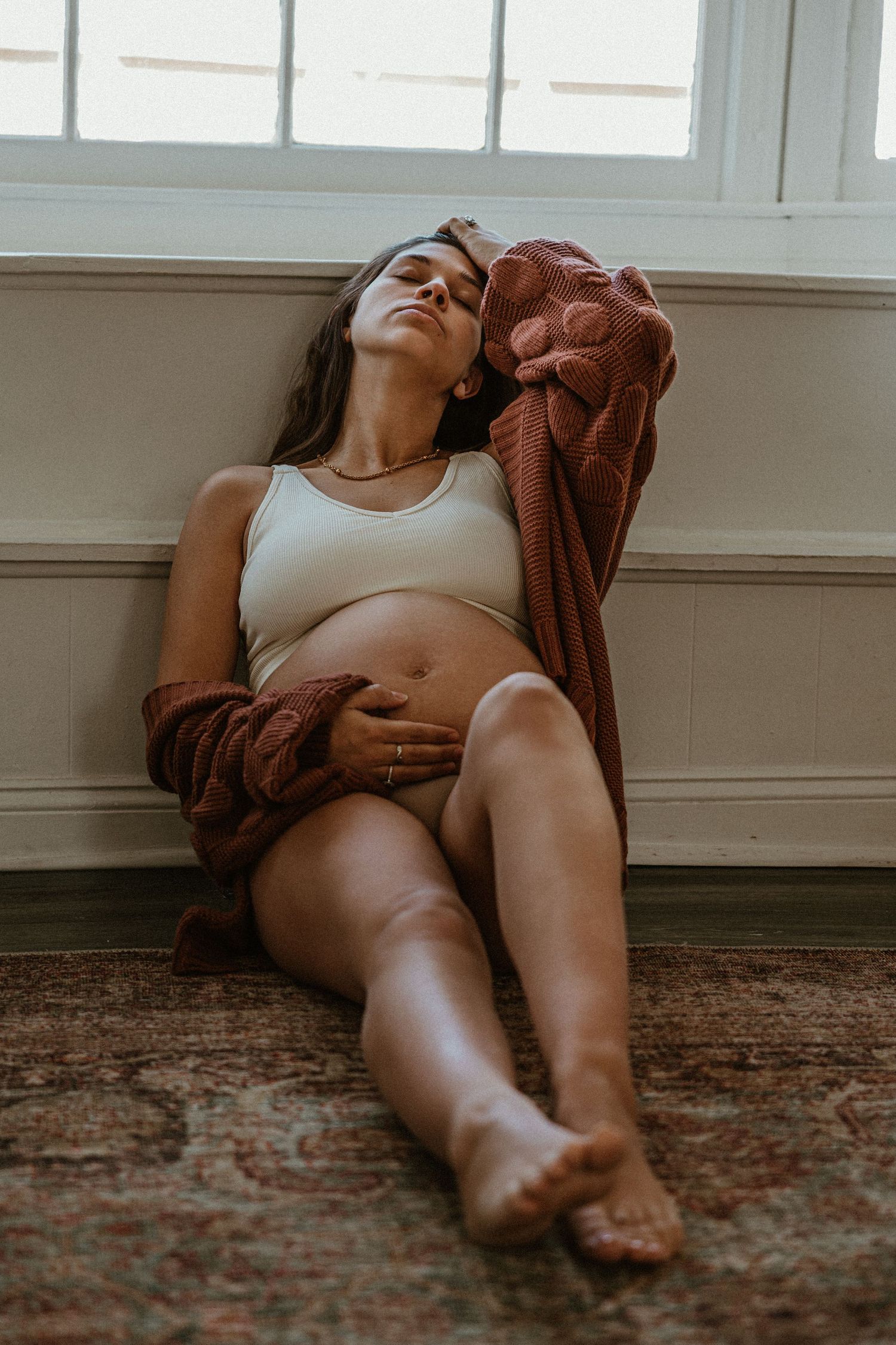 Minimalist boudoir photography session with natural window light on hardwood floors.