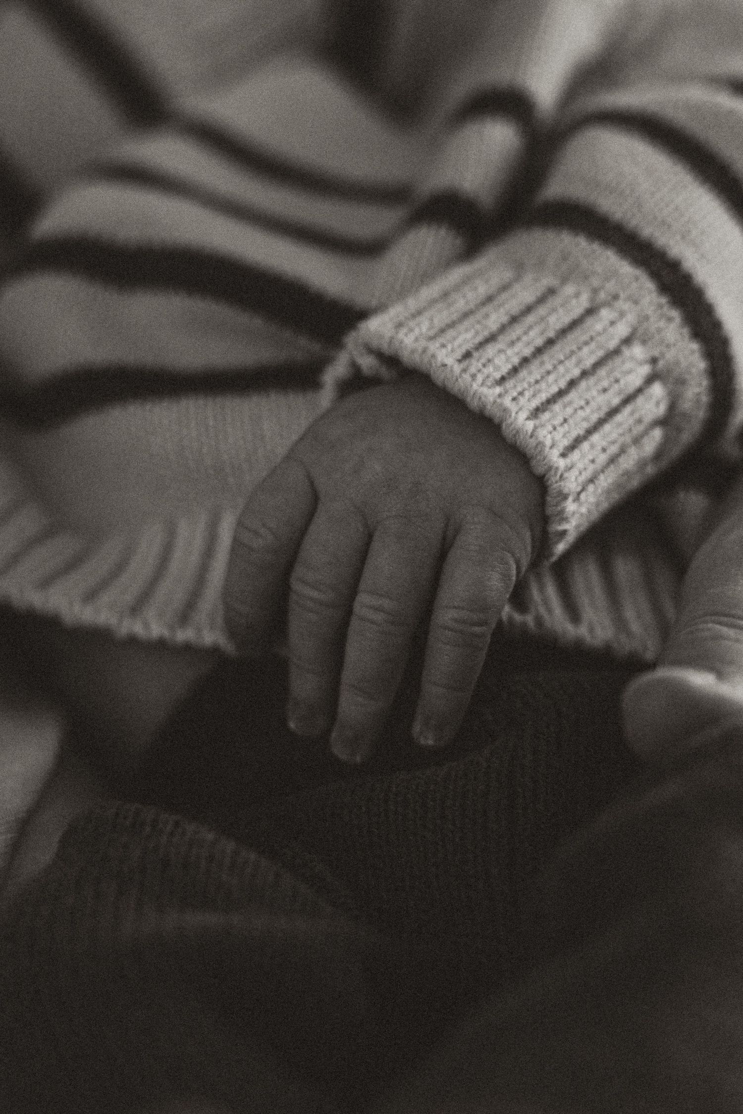 Black and white detail of small hands grasping knit fabric.