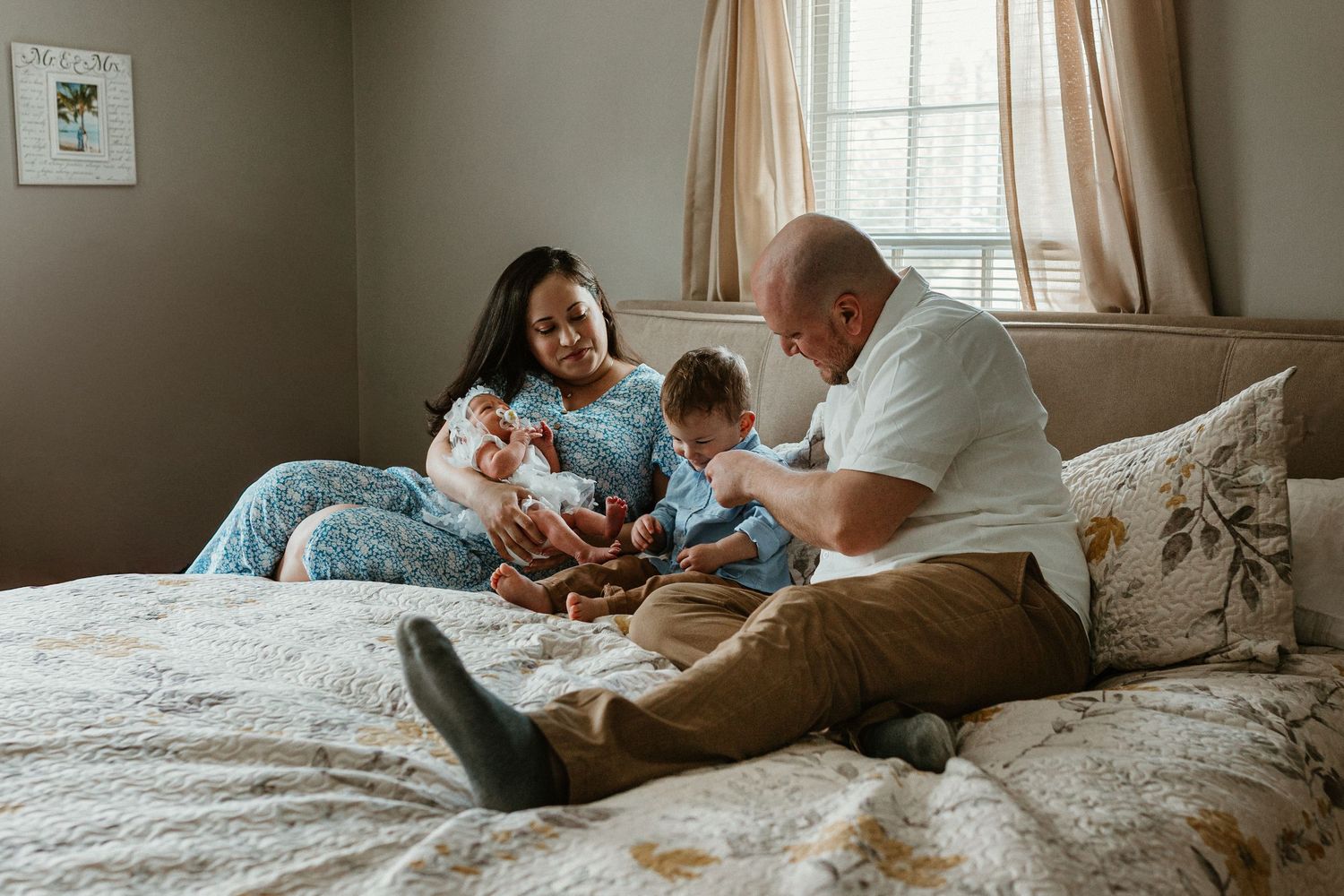 Family sharing intimate moment together on bed while holding newborn baby.