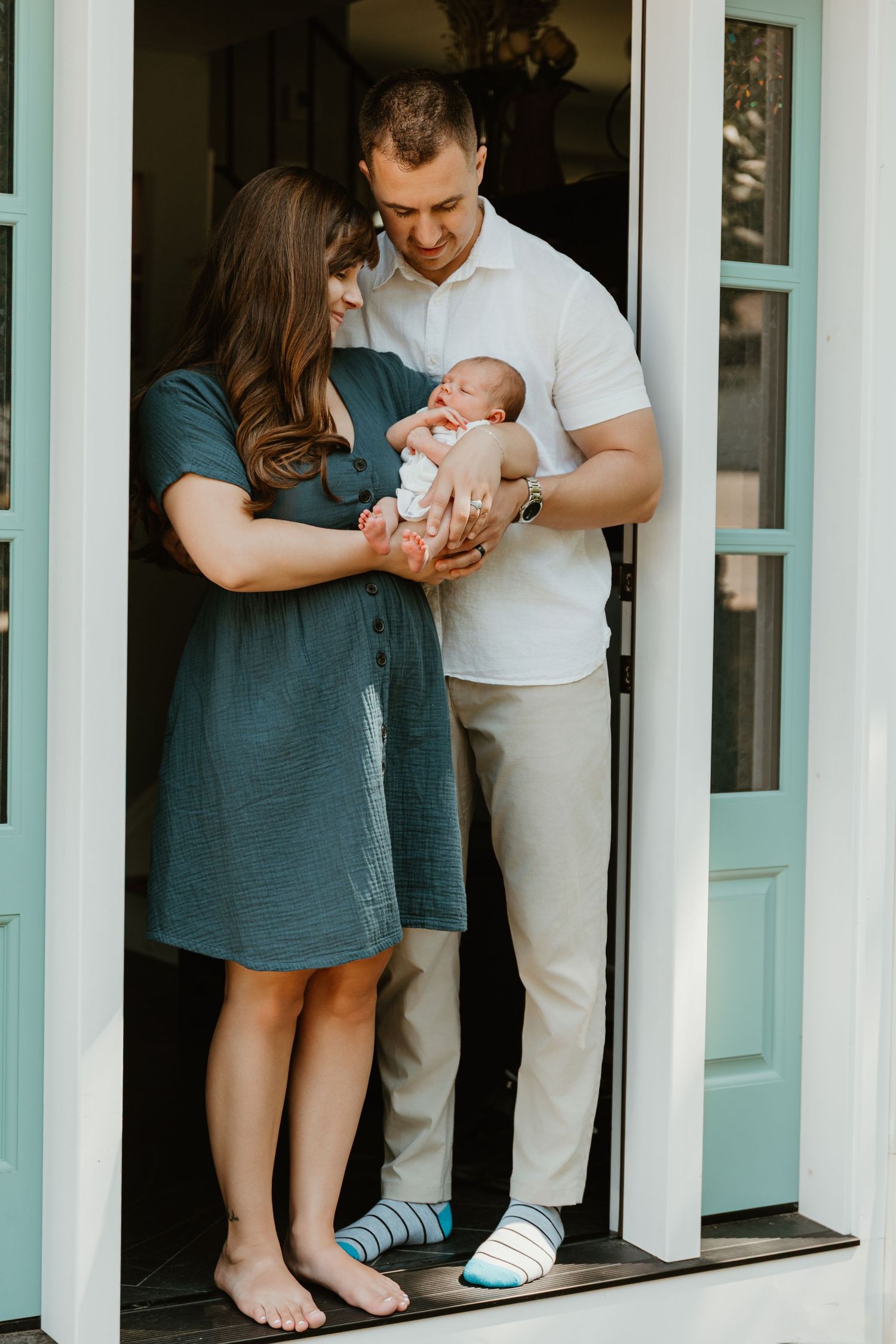 Family standing together in doorway of modern home with turquoise doors.