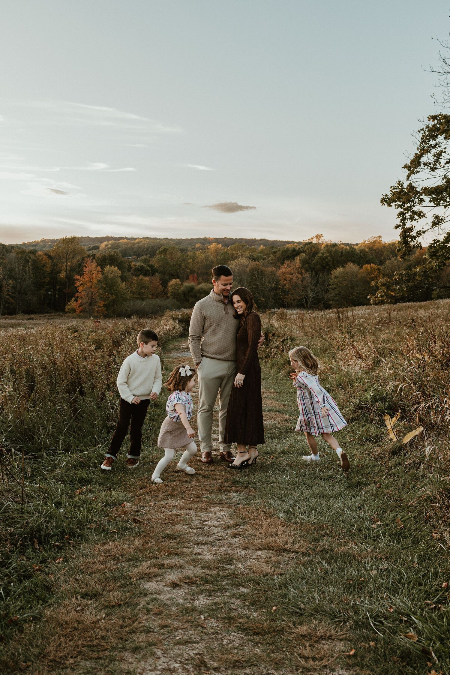 Family playing together in an autumn field during golden hour.
