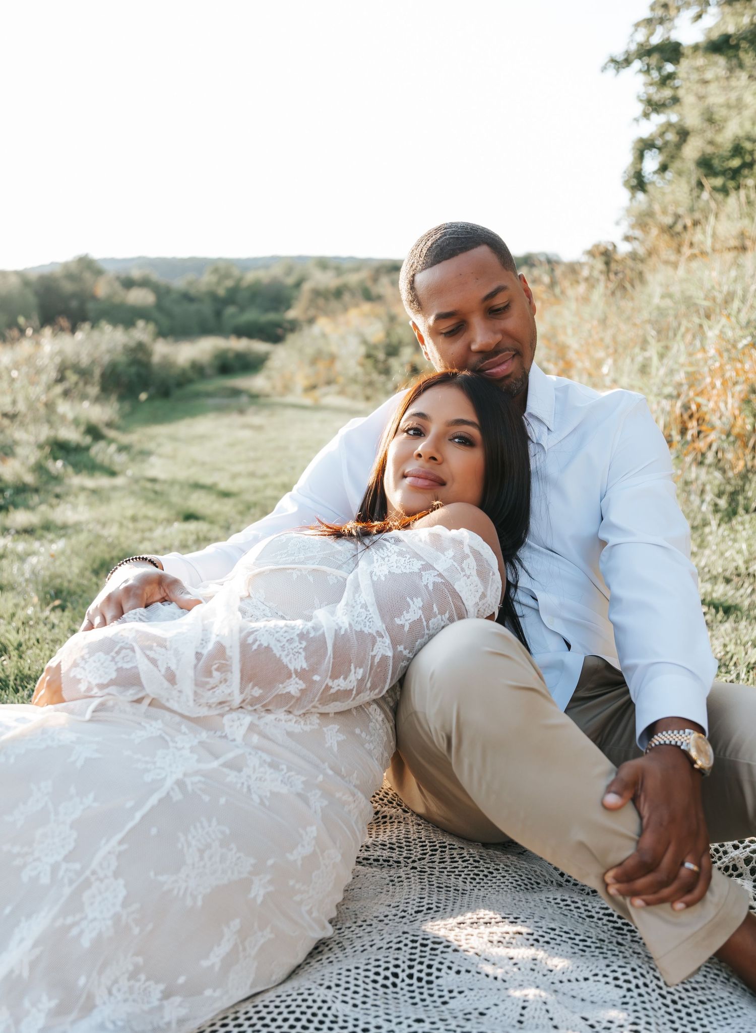 Intimate outdoor maternity photos on a blanket in nature during golden hour.