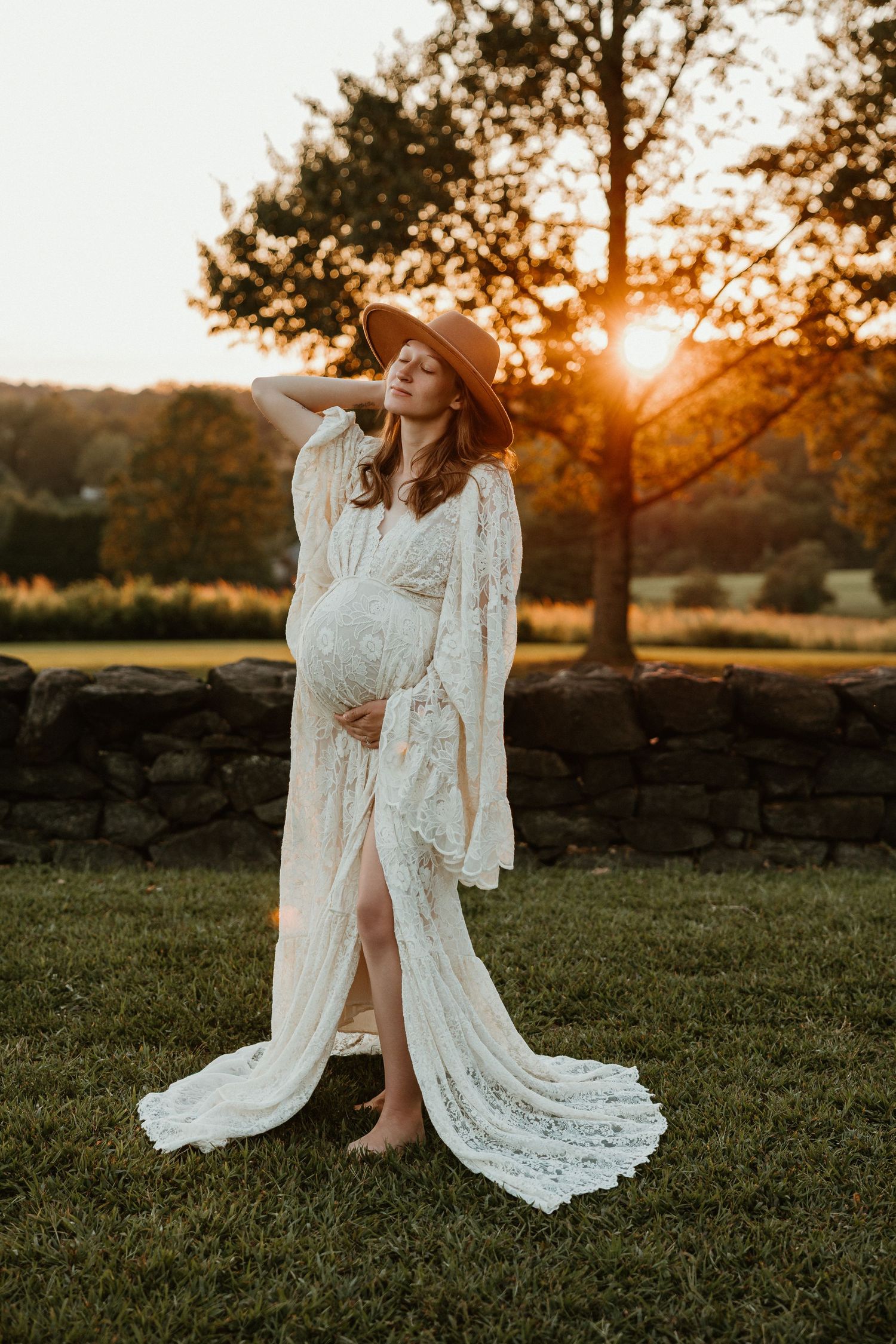 A romantic sunset maternity photo session featuring a flowing white lace dress in a grassy field.