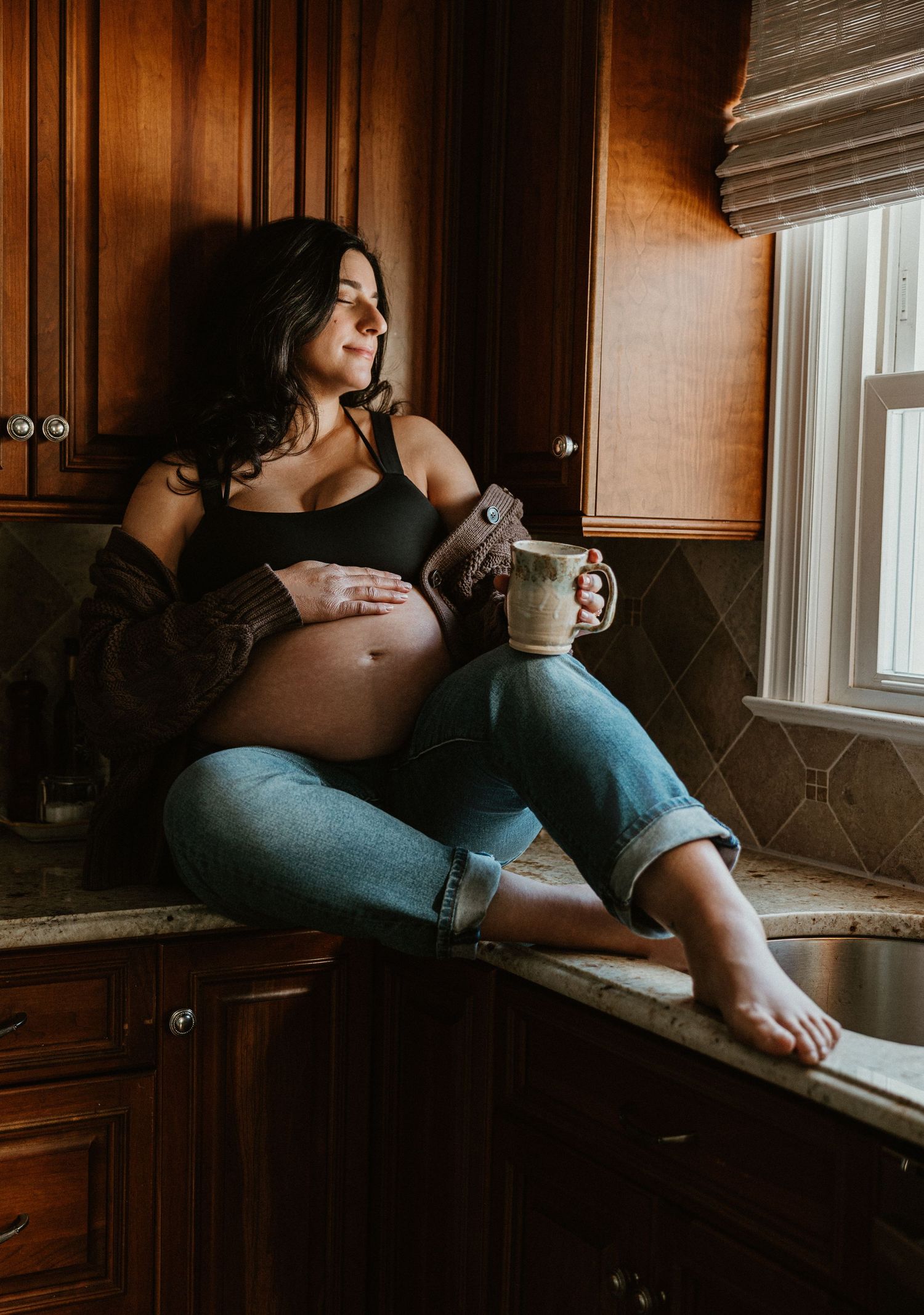 Casual lifestyle scene with person relaxing on kitchen counter by window.