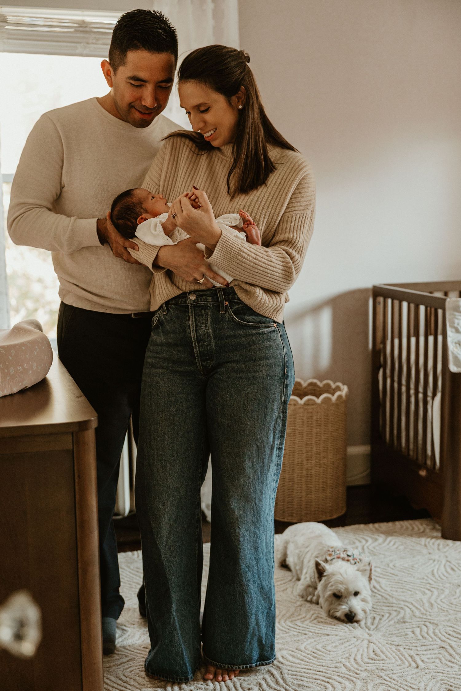 Intimate indoor family moment with a white dog visible in the background.