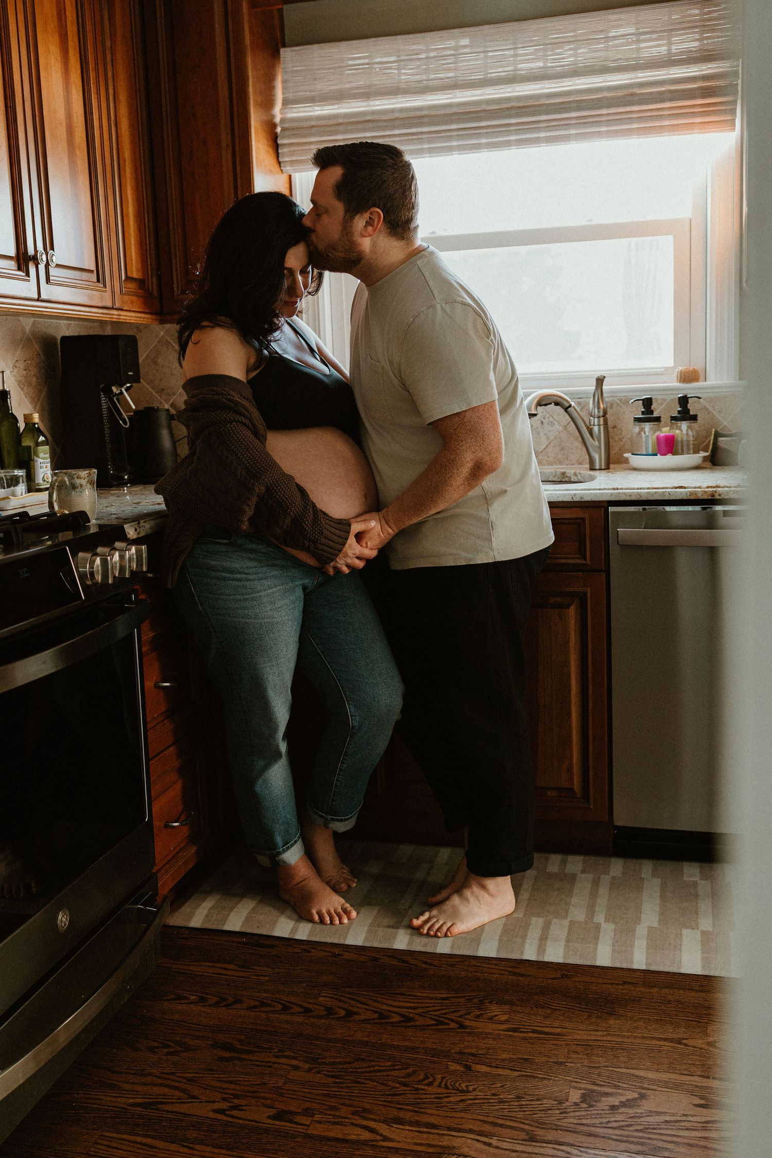 Couple shares tender moment on kitchen counter during indoor photo session.