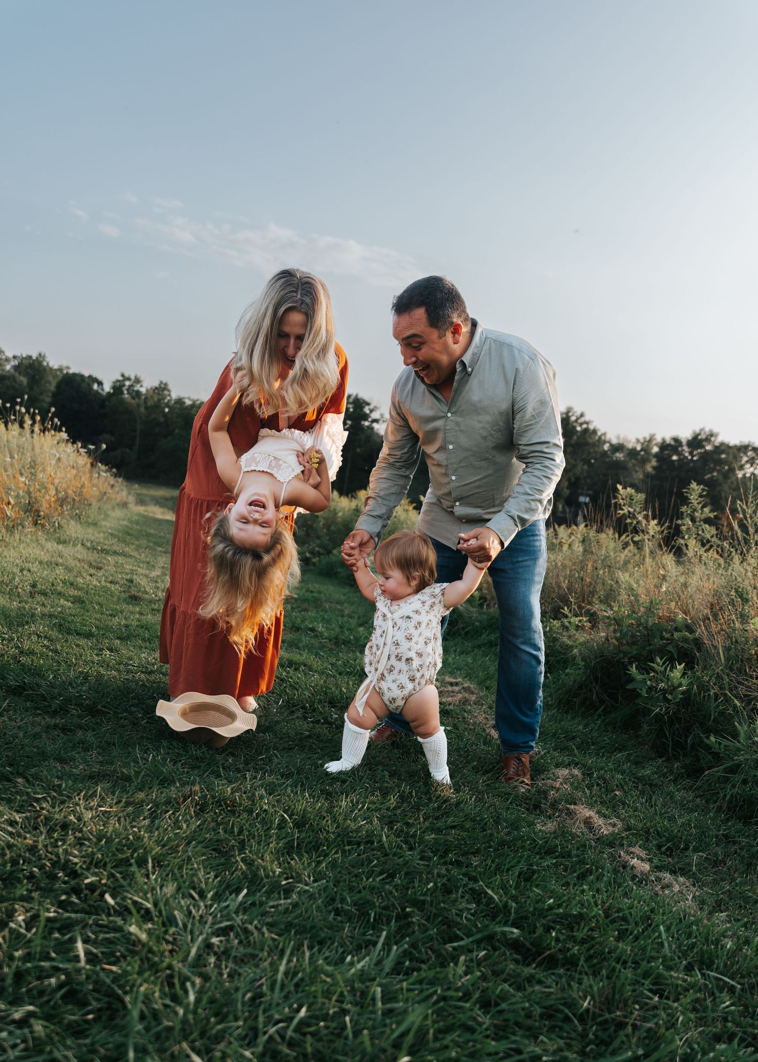 Family playing together in a grassy field during golden hour.