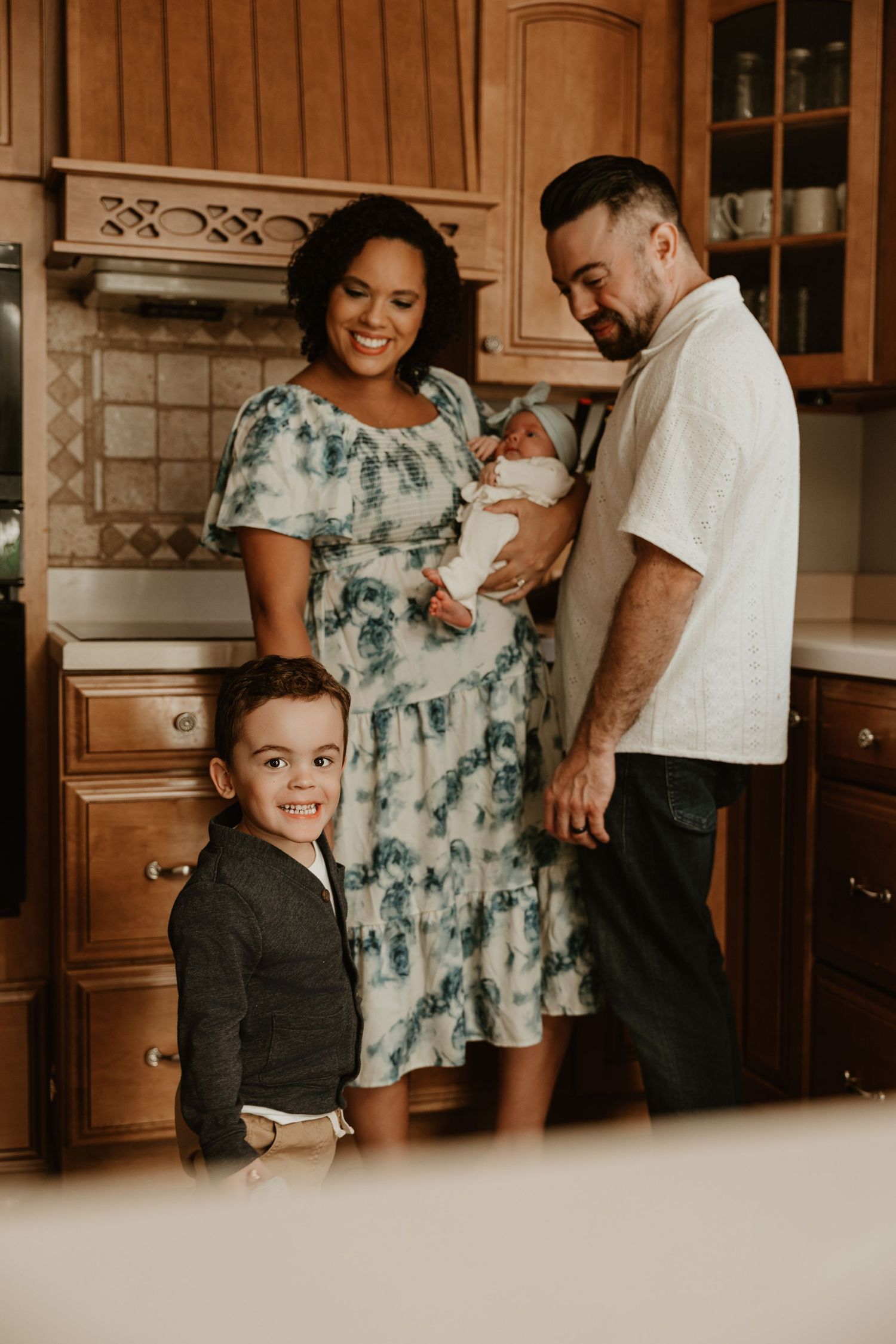 Family gathering in kitchen with warm wood tones and natural lighting.