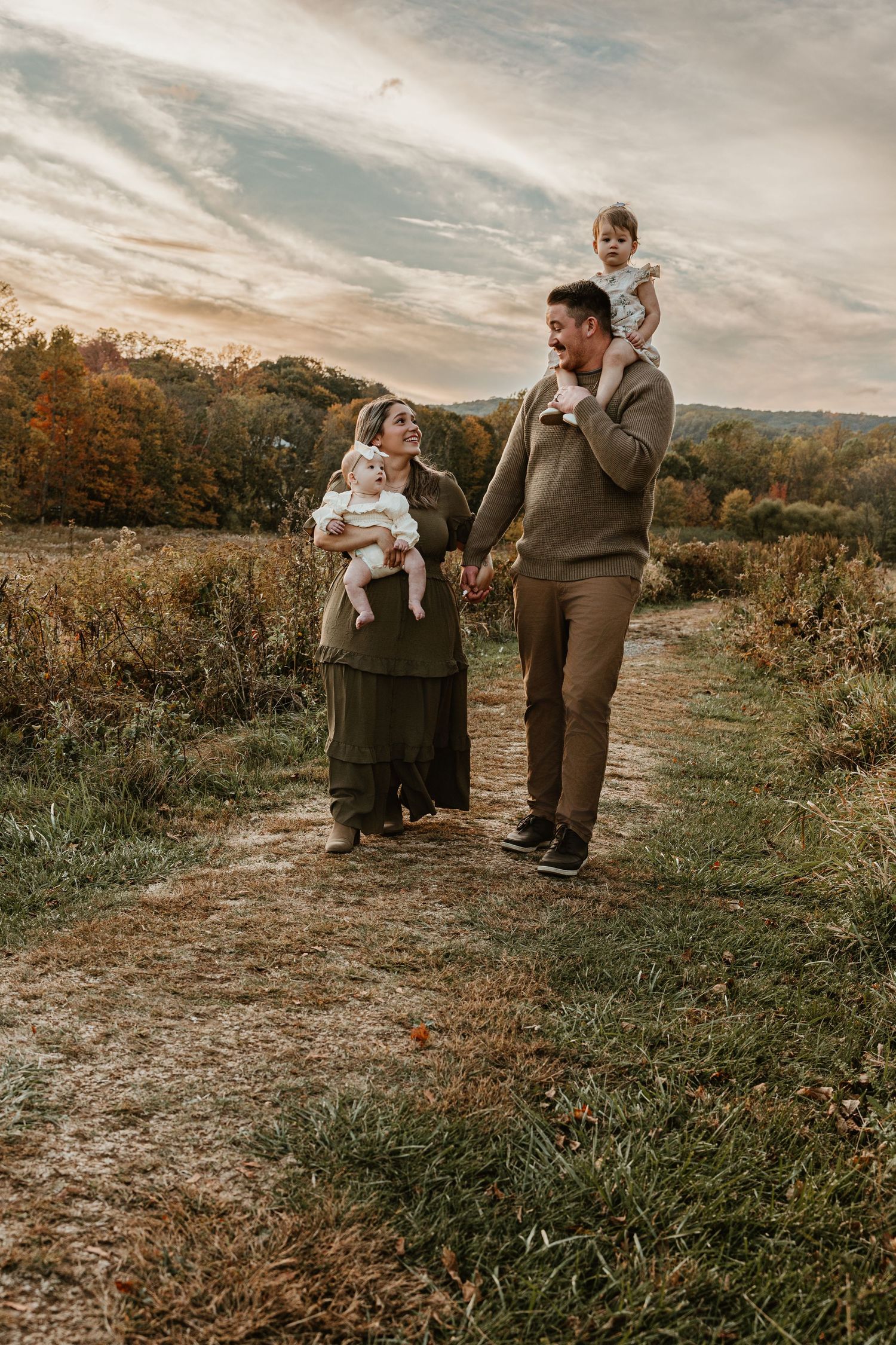 Family enjoying outdoor moments together on a hilltop during golden hour.