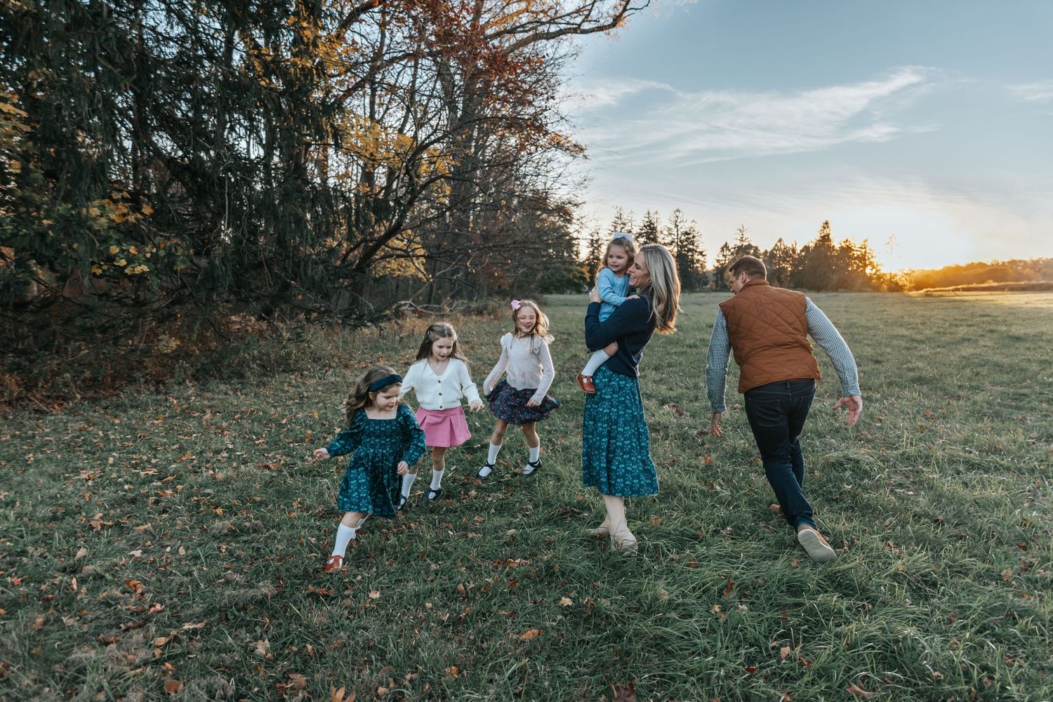 A series of distant shots showing a family running and playing in a golden-lit field.