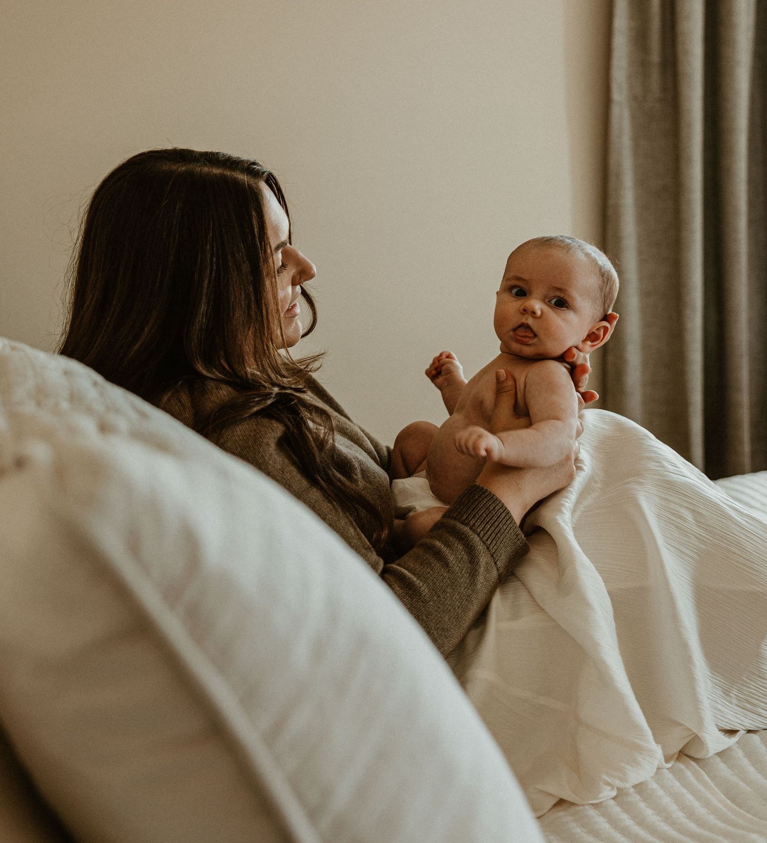 Intimate lifestyle photos of a family relaxing together on white bedding.