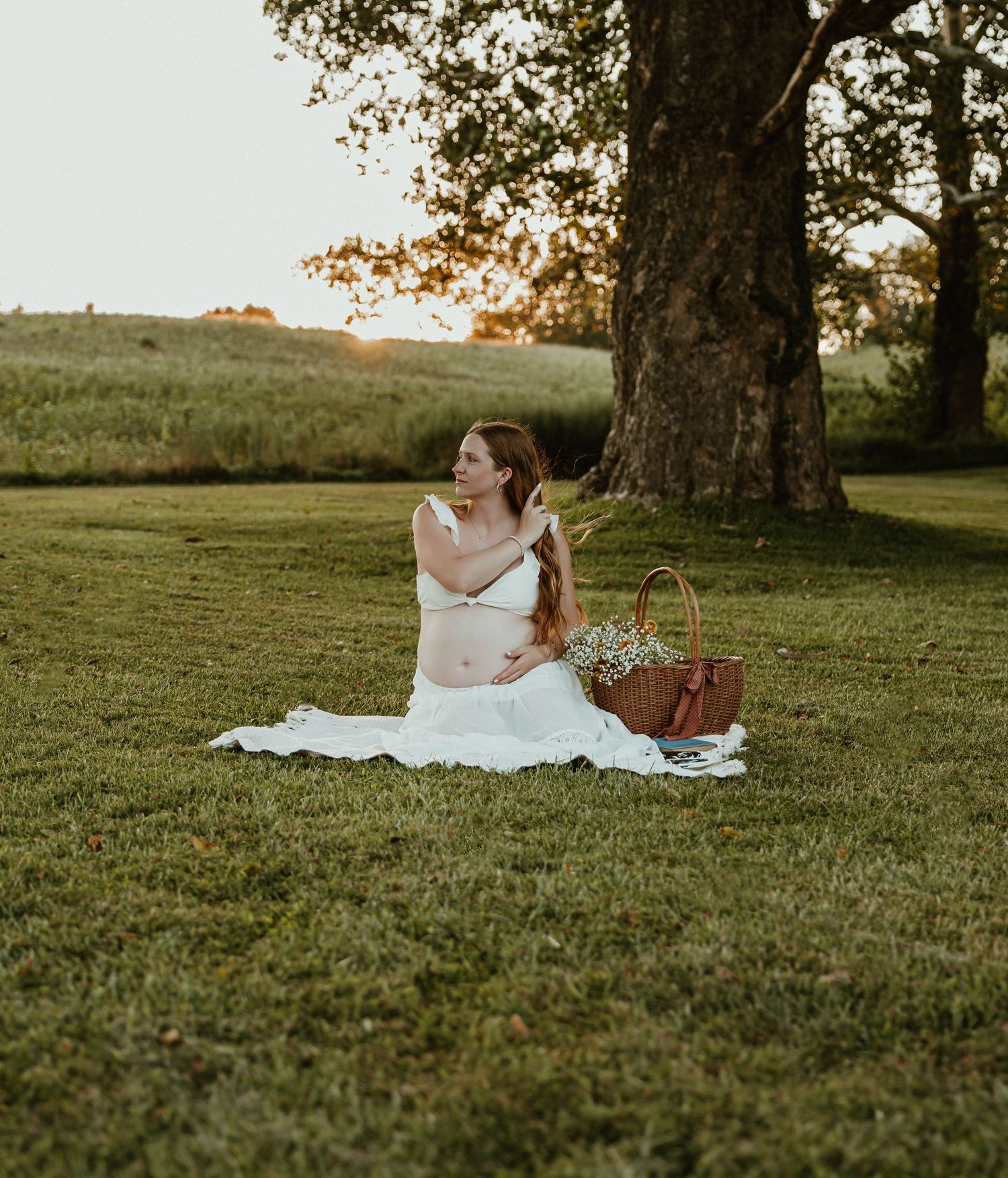 White picnic blanket spread out on grass under trees at sunset.