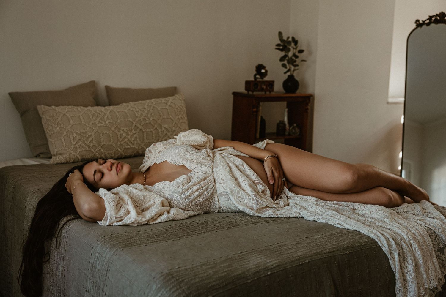 Artistic boudoir photography on white bedding with soft natural window light.