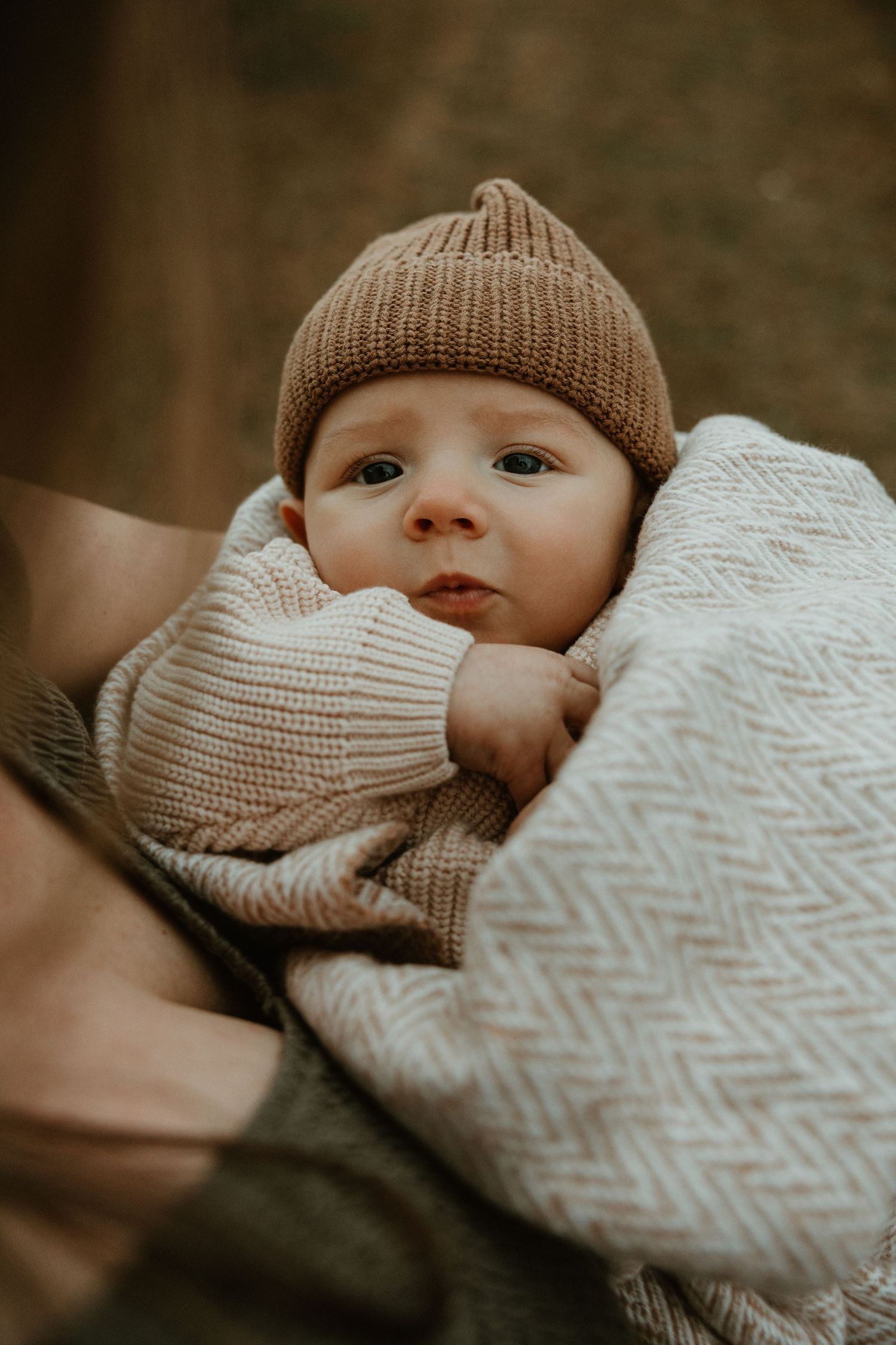 Close-up shots of a baby wearing a knit beanie wrapped in a chevron patterned blanket.