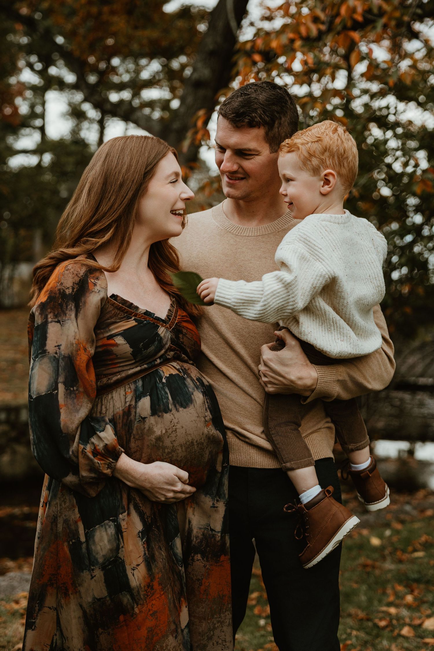 Family shares tender moments together outdoors in coordinated neutral fall outfits.