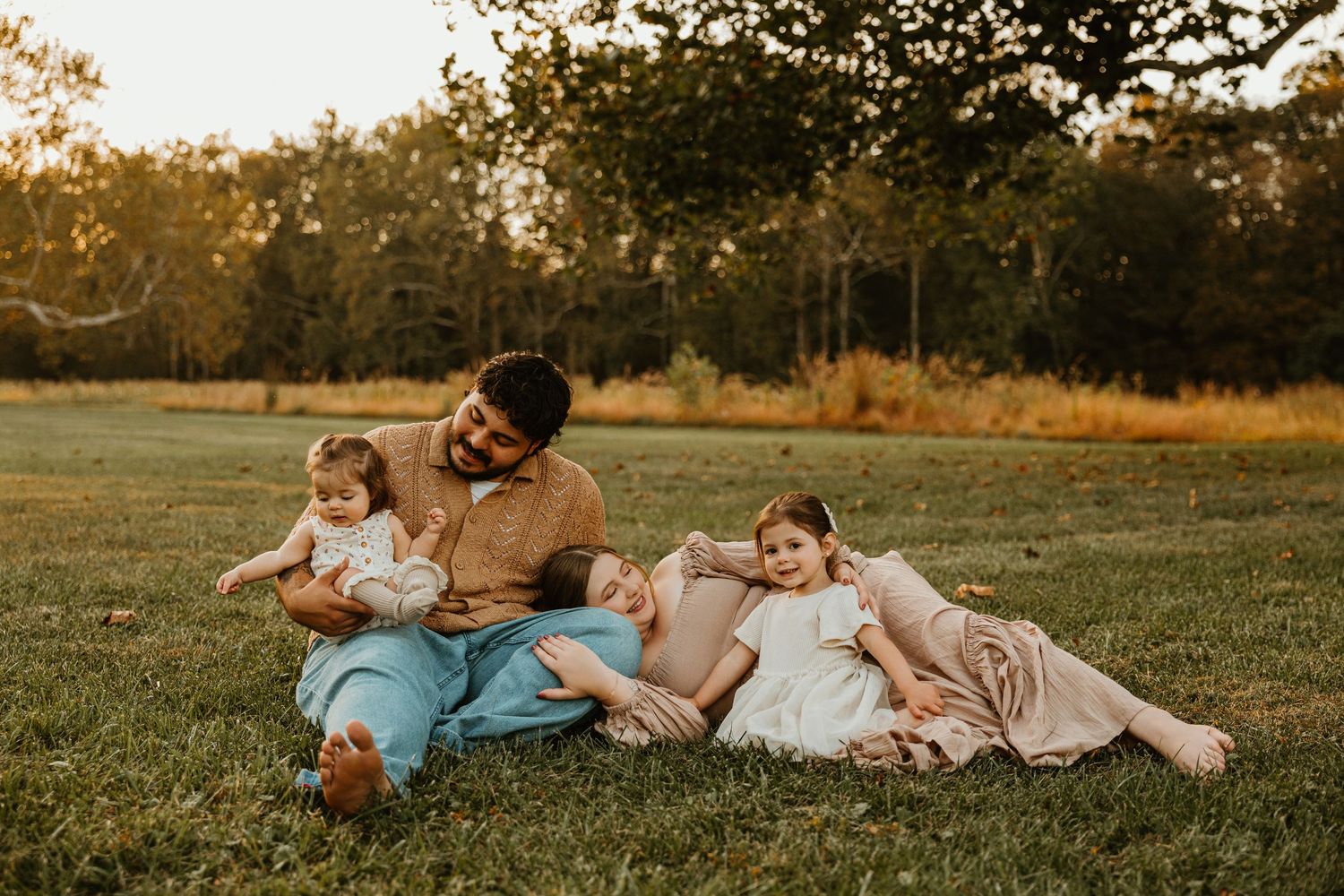 A family plays together on a grassy field during golden hour.