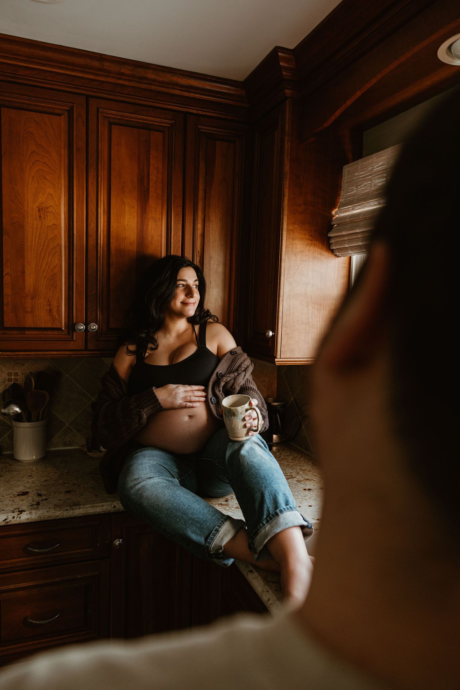 Intimate lifestyle photography session in a dimly lit kitchen with warm tones and natural lighting.