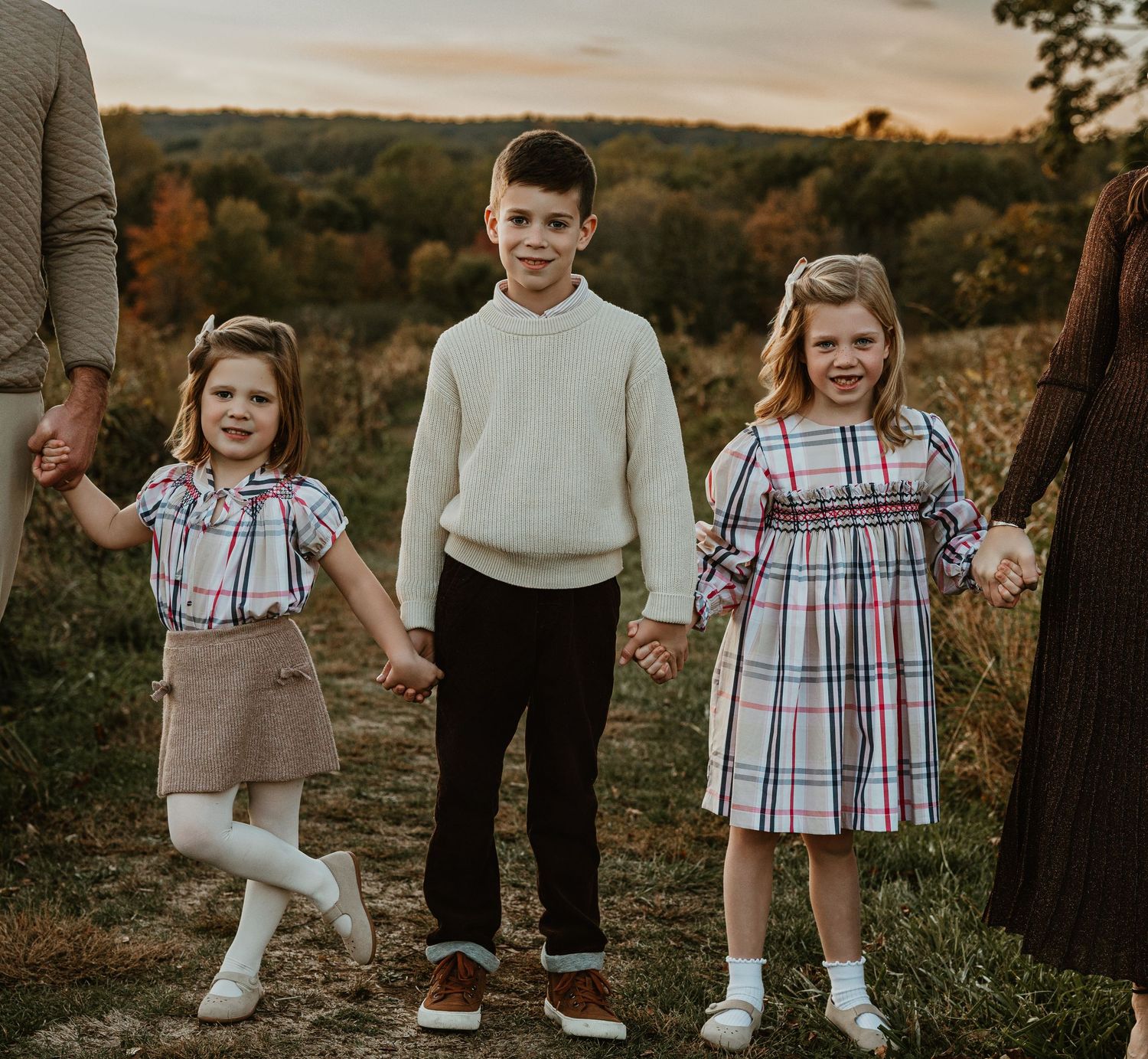 Children standing together in coordinated outfits during an outdoor autumn photoshoot.