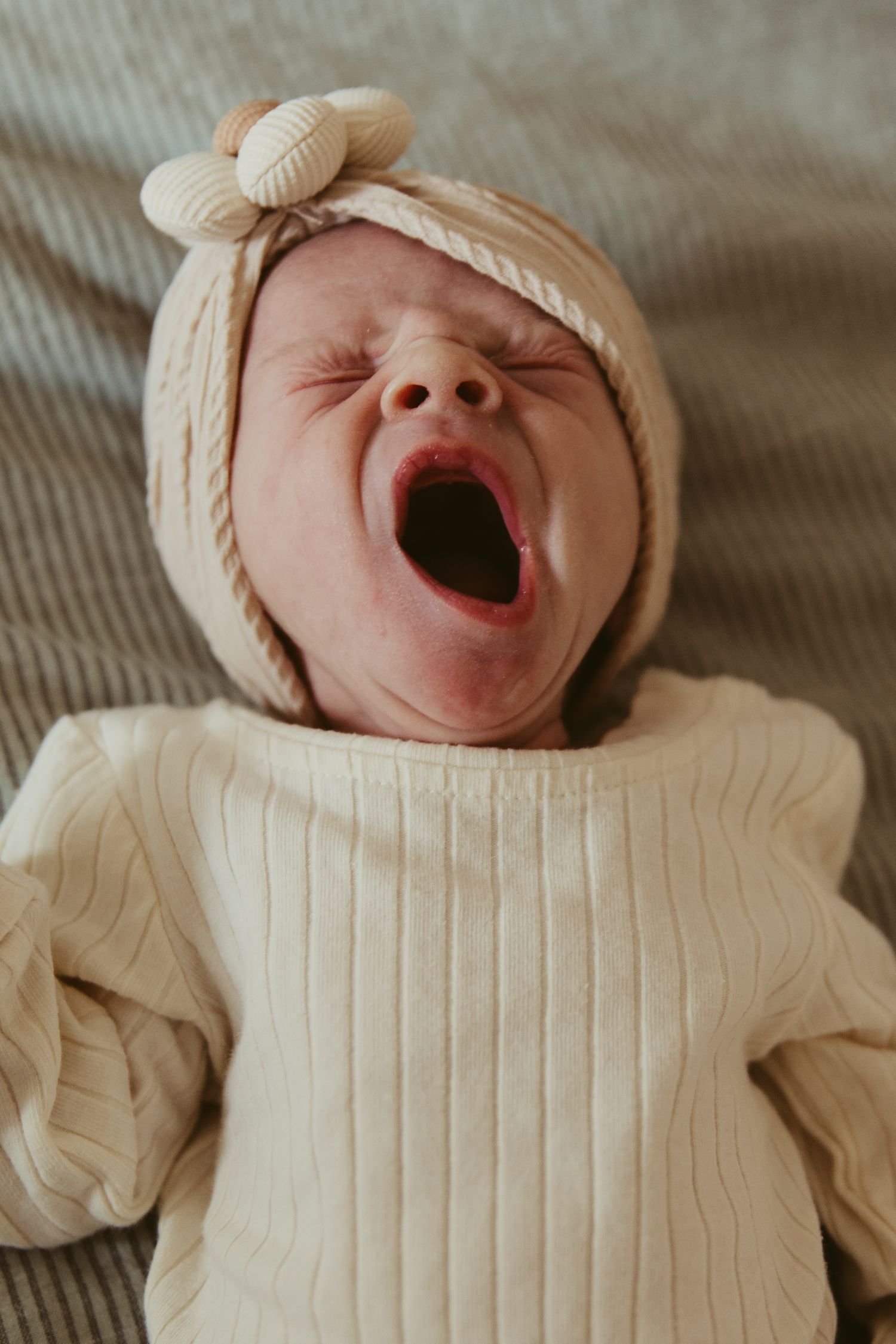 Series of close-up shots showing a baby in cream knit clothing yawning and making expressions.