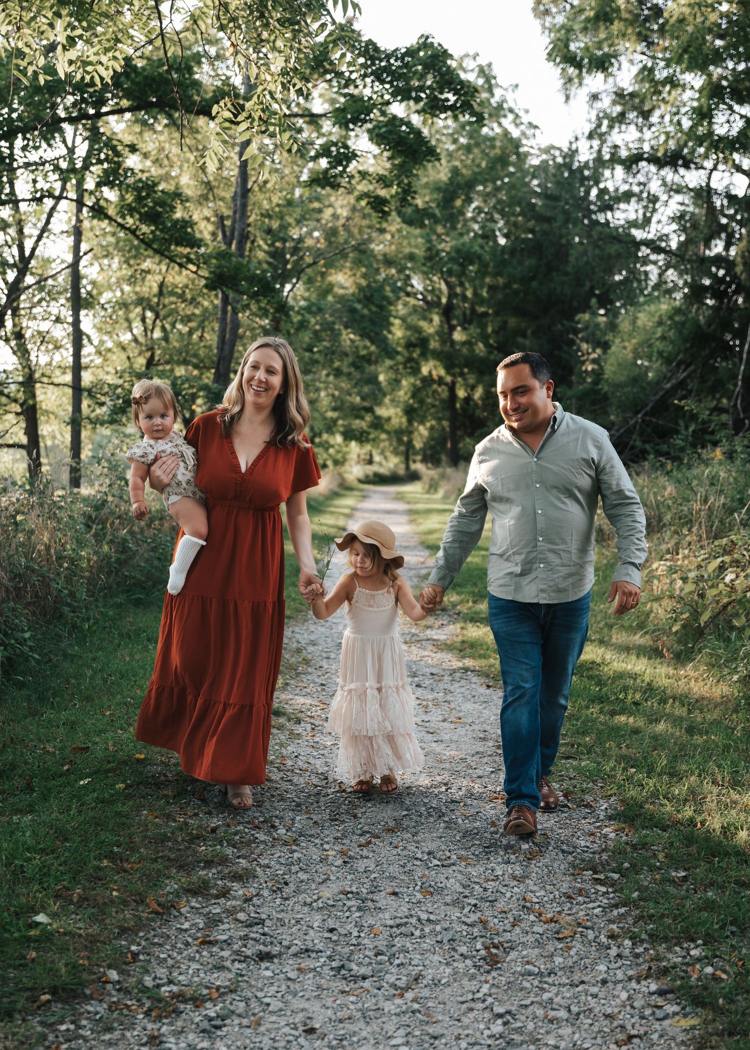 Family walking together on a gravel path through a green wooded area.