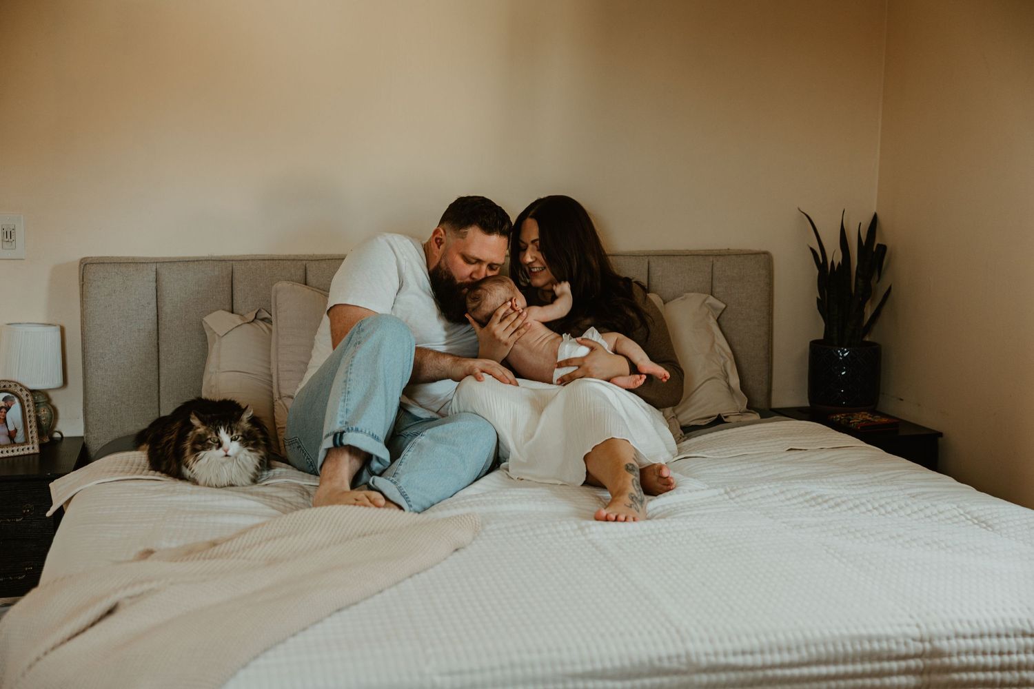 Family lounging together on a large bed during an in-home photography session.
