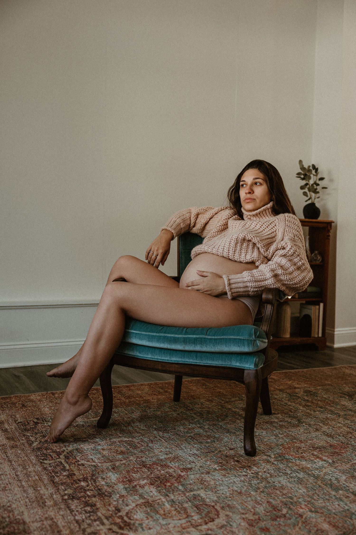 Relaxed boudoir session on vintage teal chaise lounge with pink sweater.