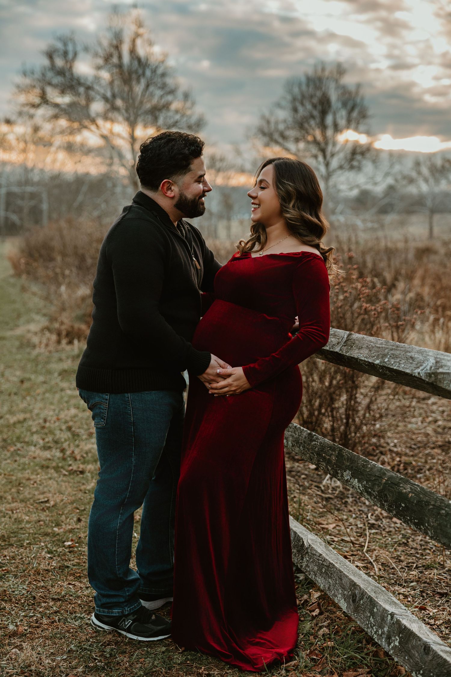 Romantic couple embraces by a rustic fence during an autumn sunset session.