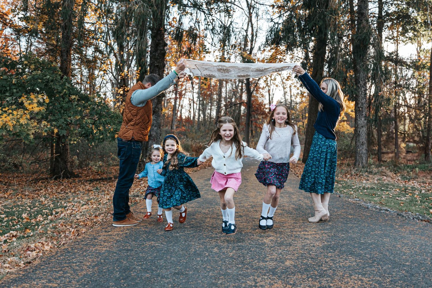 Family walking together on a nature trail surrounded by autumn trees.
