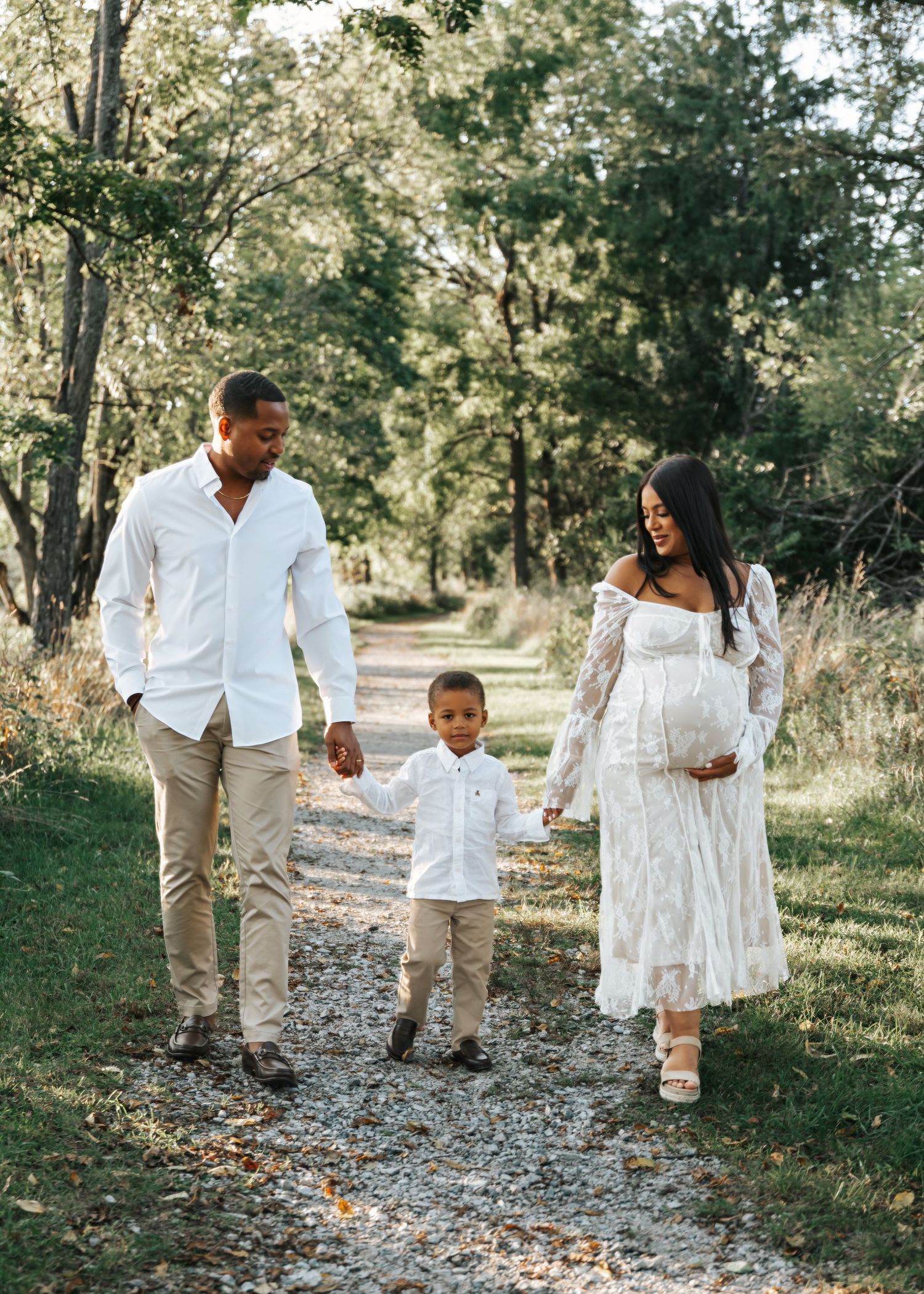 Family walking together on a tree-lined path wearing coordinated white outfits.