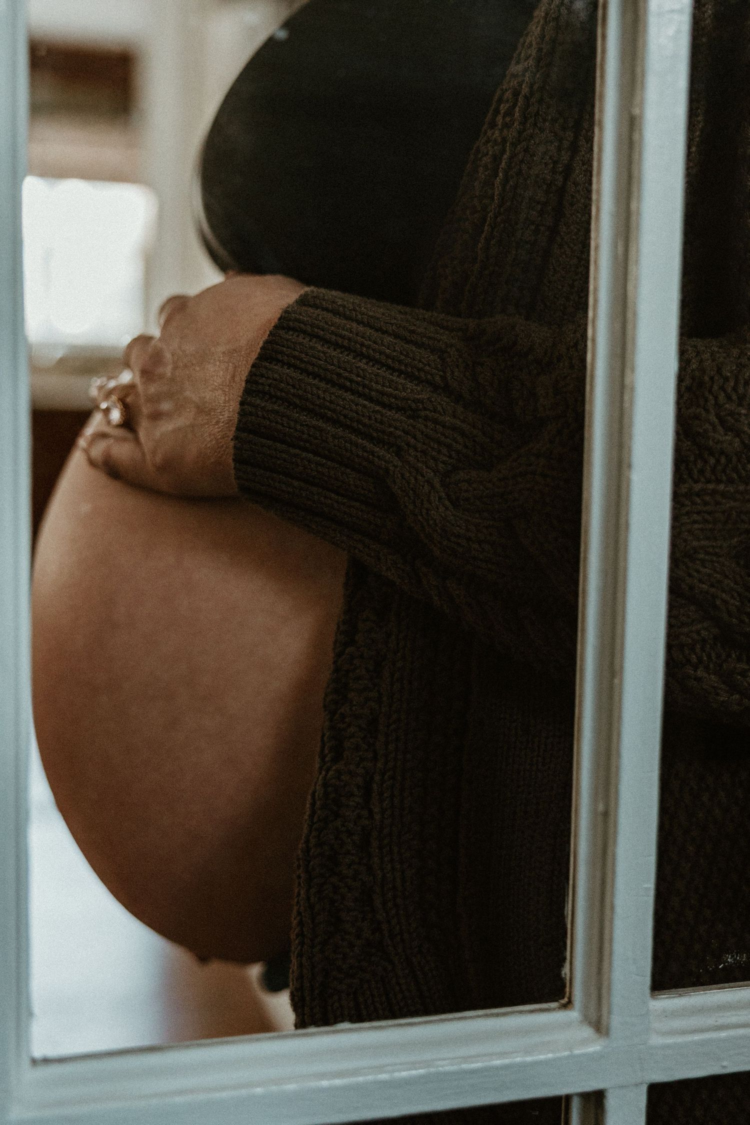 Close-up maternity photos showing pregnant belly through window reflection.