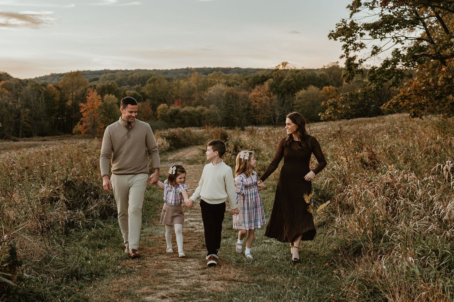 A family walking together through a golden autumn field at sunset.