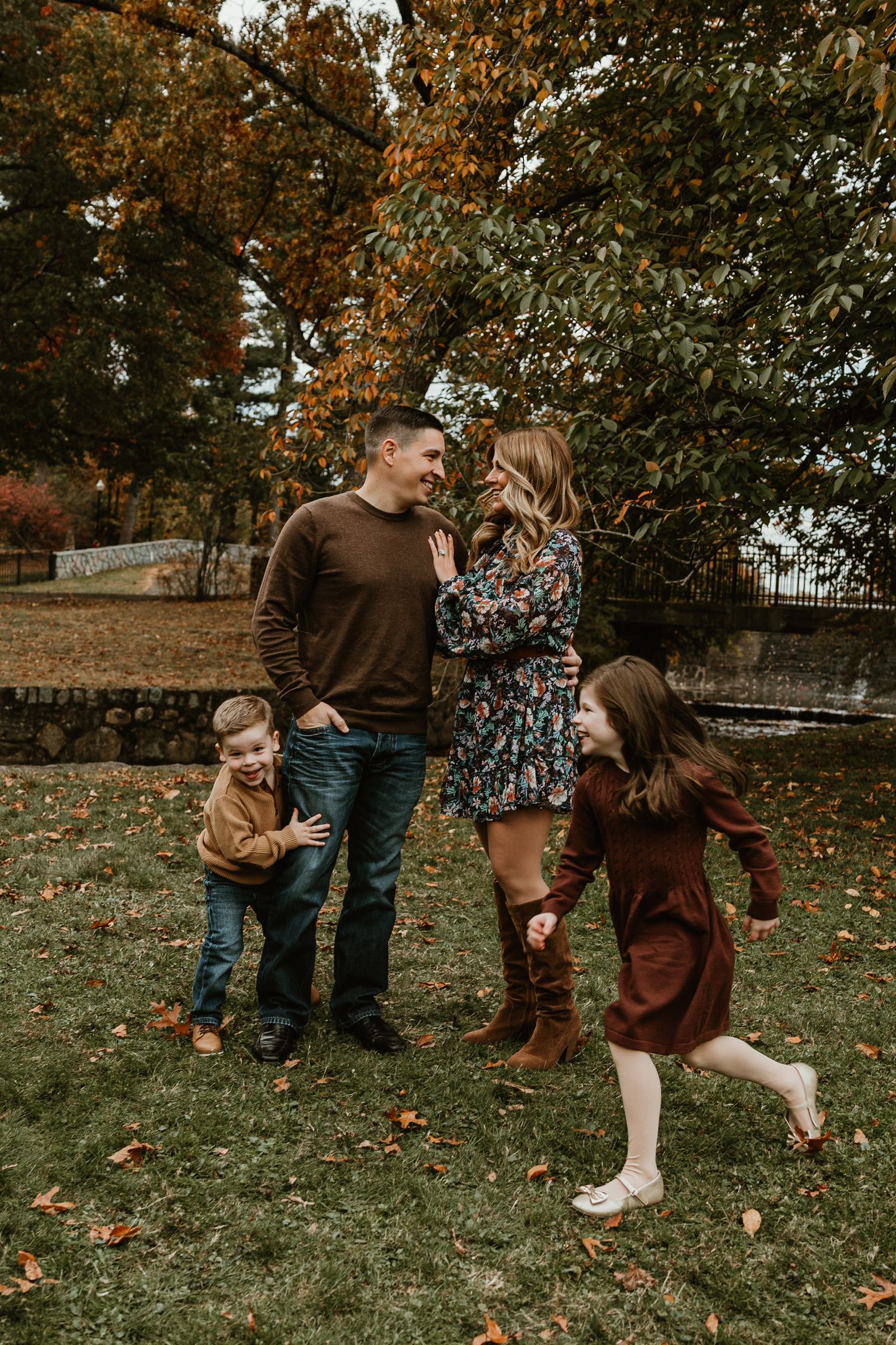 Playful family moment captured in autumn setting with falling leaves.