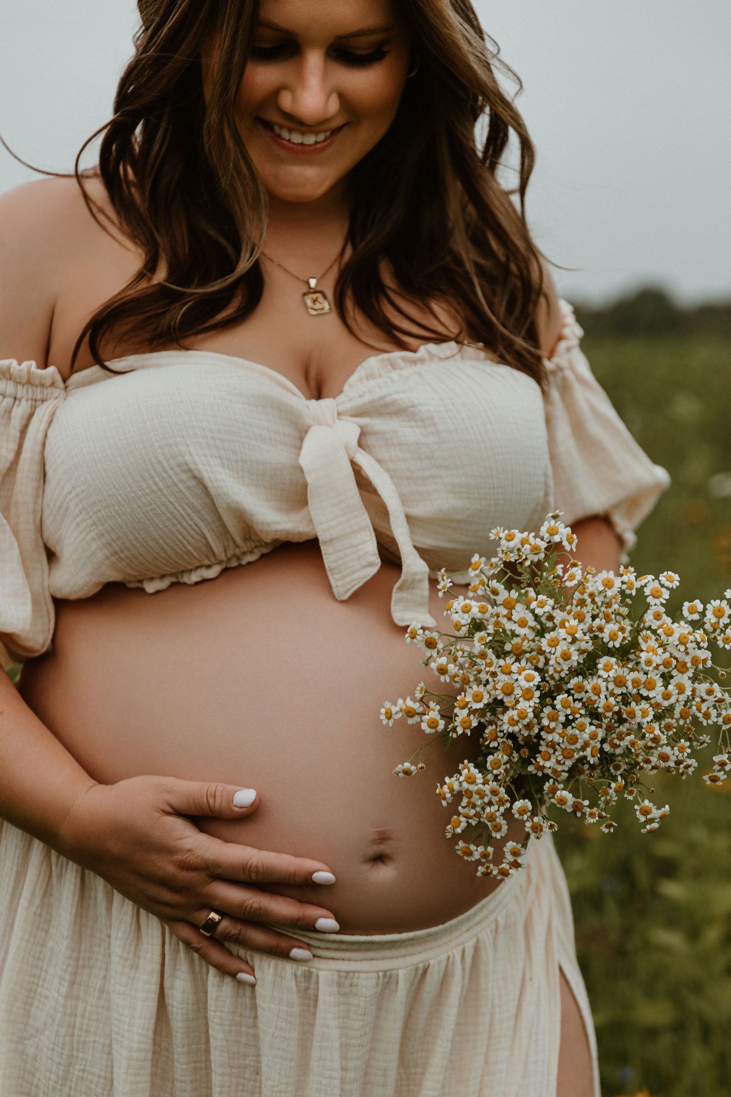 Maternity photo featuring white dress and delicate wildflower bouquet.