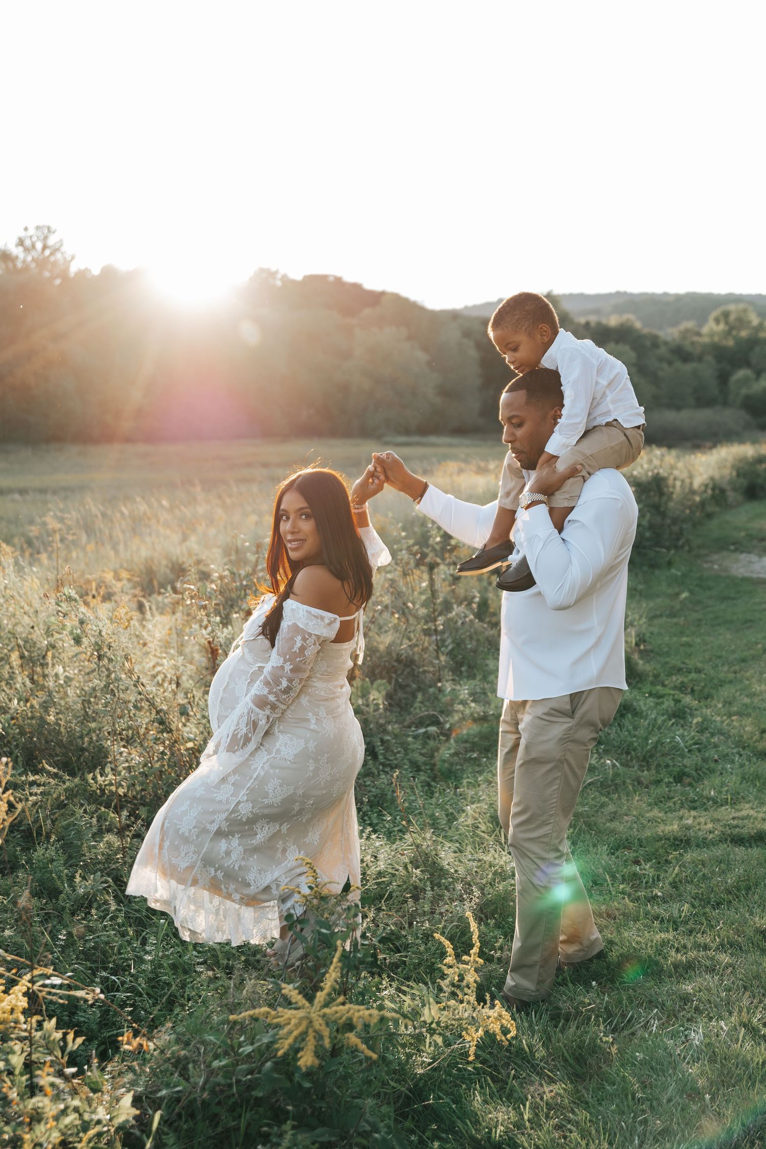 Playful family moment captured in a meadow during golden hour.