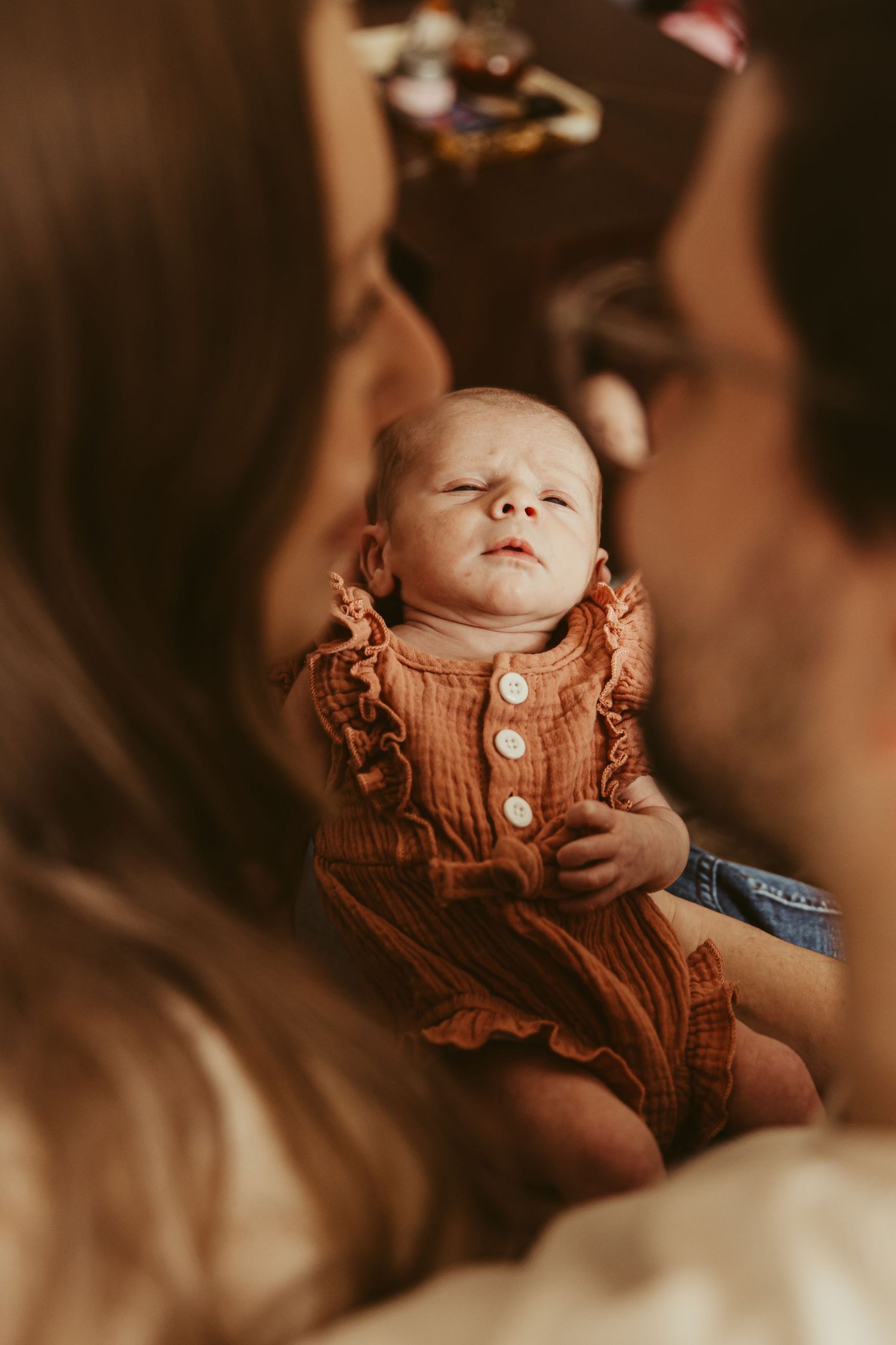 Baby wearing ruffled rust-colored outfit during tender moment.