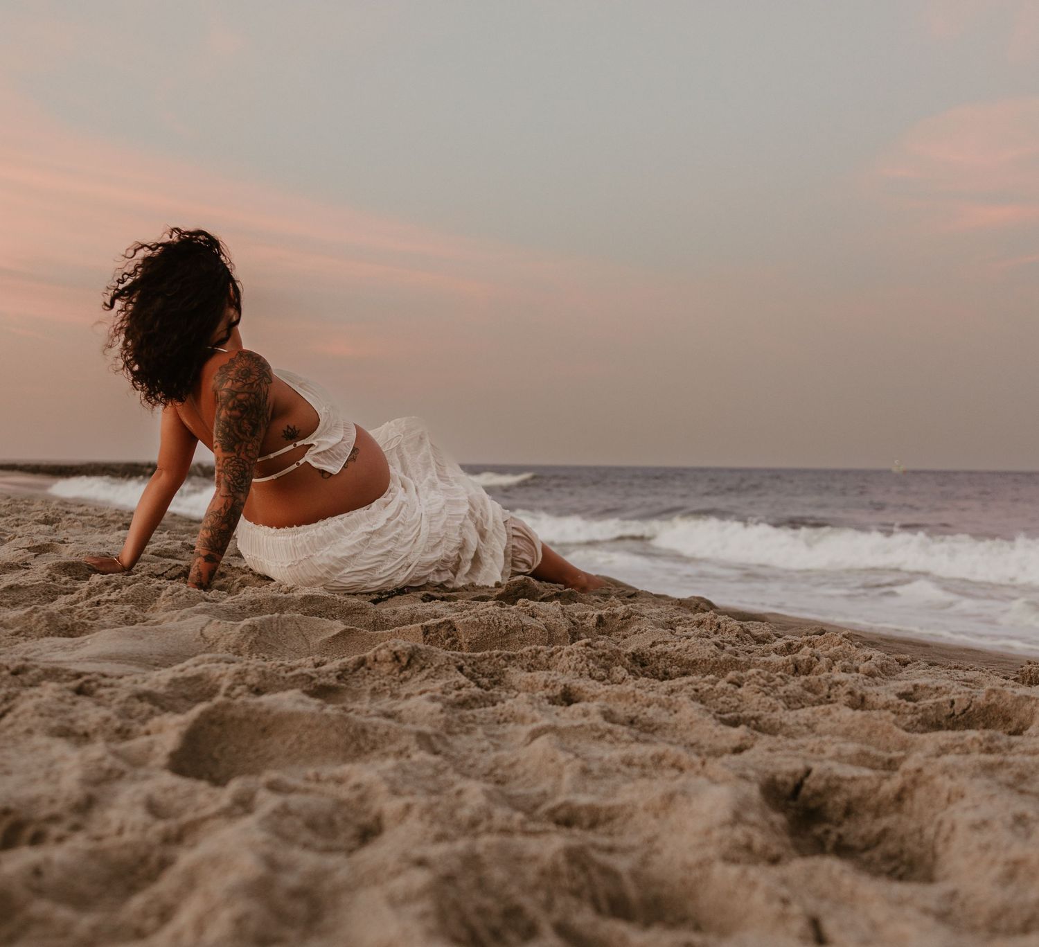 Couple walking and playing on a sandy beach at sunset.