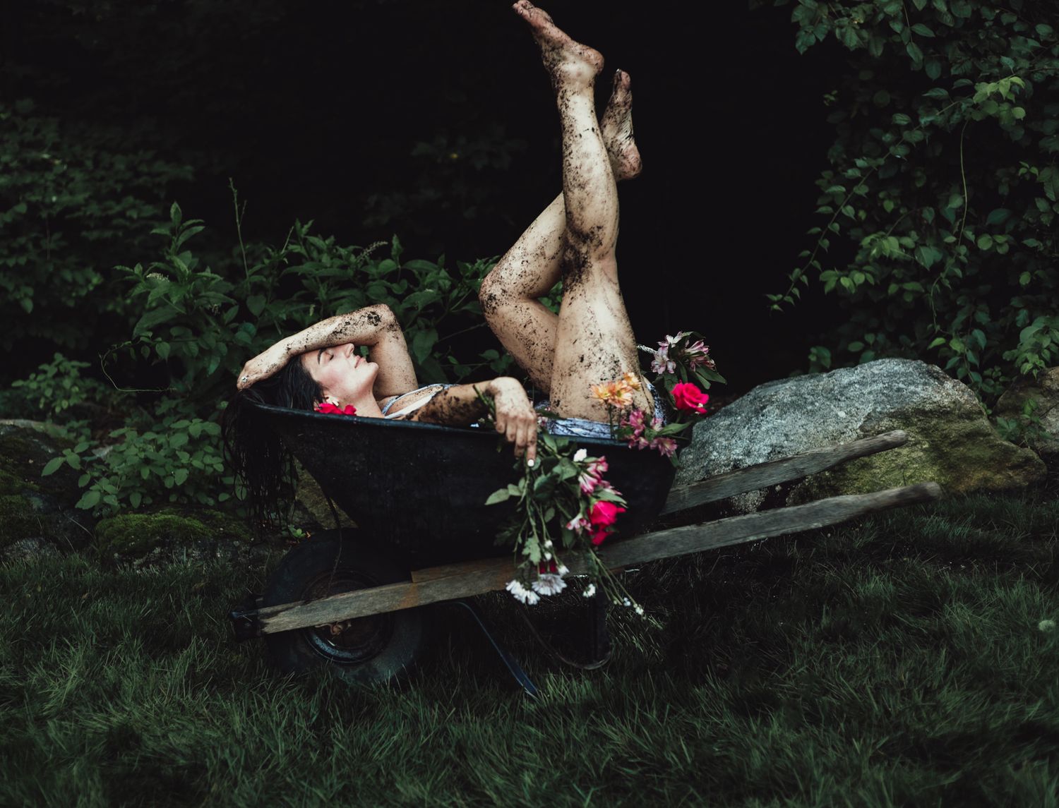 girl in wheelbarrow holding flower, emotional, raining, garden, dramatic, lifestyle, creative photoshoot, themed